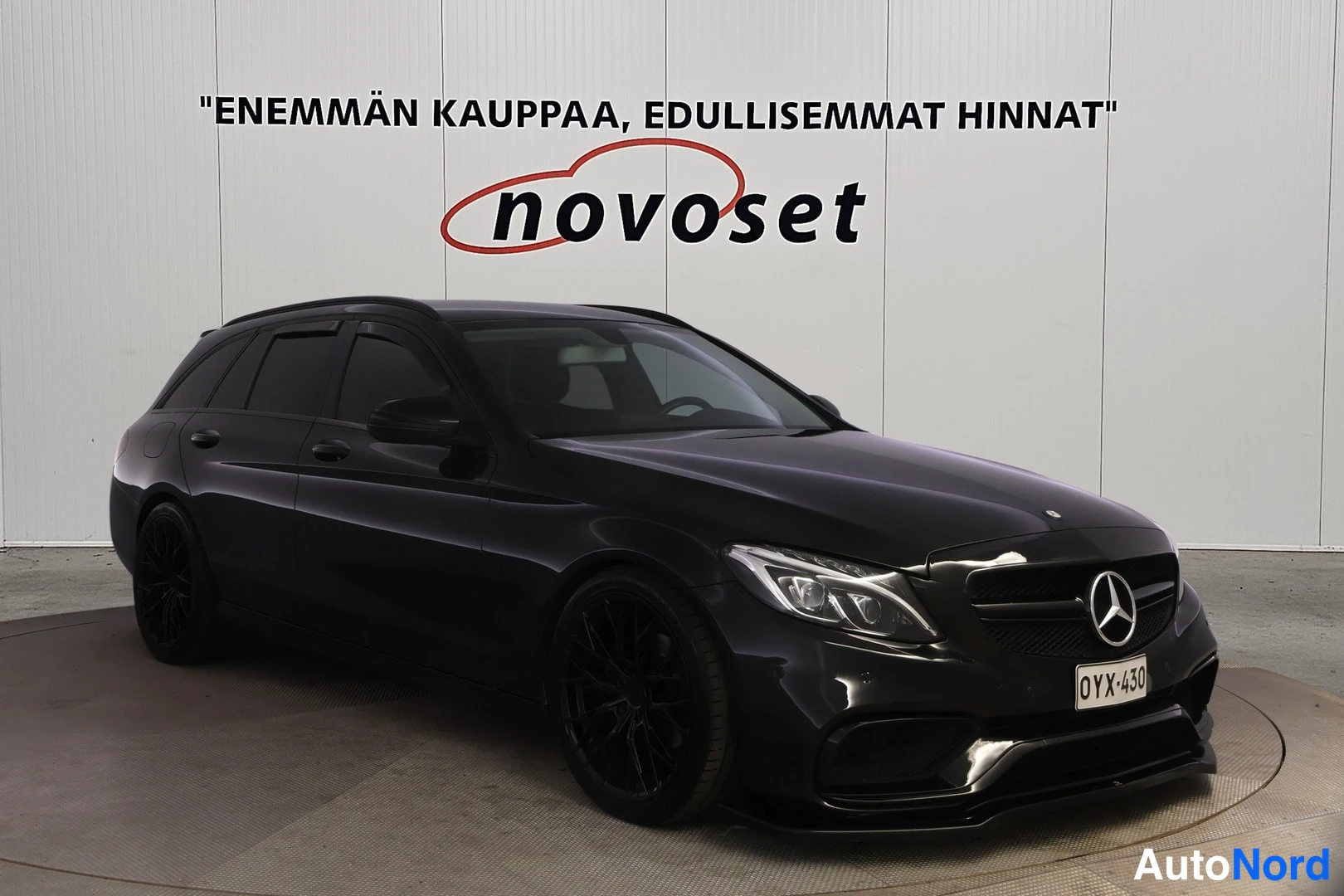 Etuviisto, nokka oikealle: Musta Mercedes-Benz -farmari etukulmasta oikealle suunnattuna, rekisterikilpi.