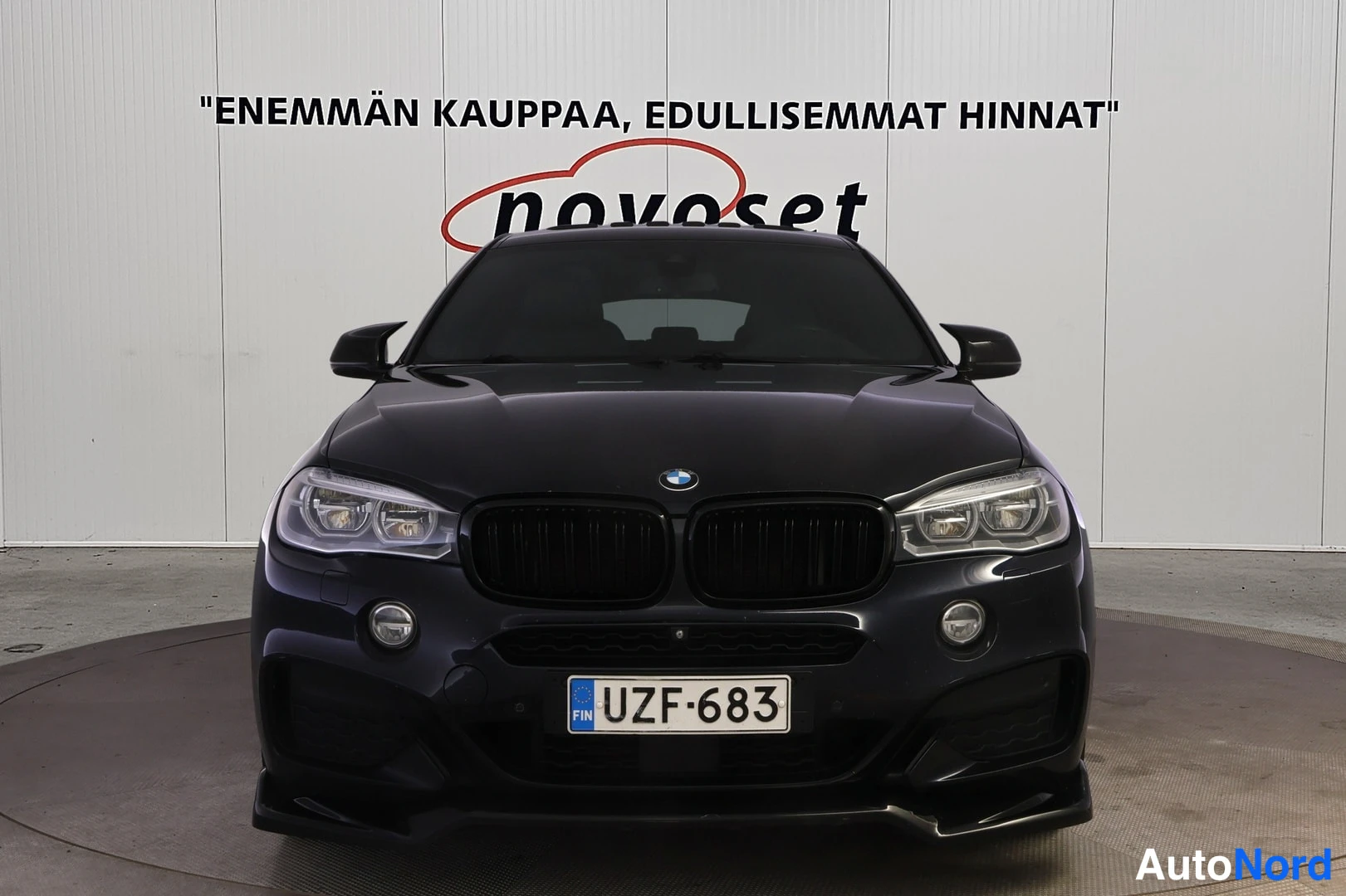 Edestä: Mustan värisen tilavautomobiilin suora etunäkymä; etusäleikkö, ajovalot ja rekisterikilpi näkyvät.