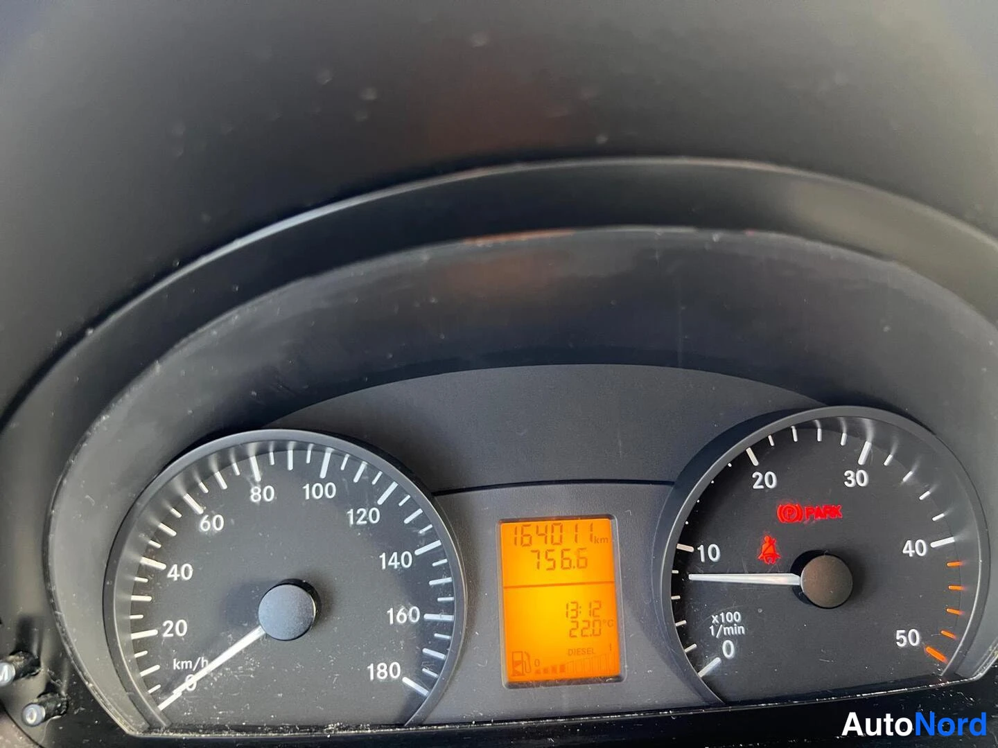 Muu: Kojelautan mitat lähikuvassa; nopeusmittari 0-180 km/h, kierroslukumittari ja oranssi LCD-näyttö, jossa lukemat 164011 km ja 7566.