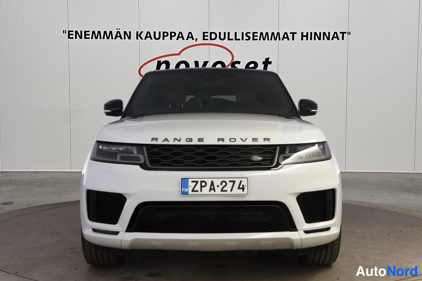 Edestä: Valkoinen Land Rover Range Rover Sport suoraan edestä, musta etusäleikko ja rekisteritunnus.