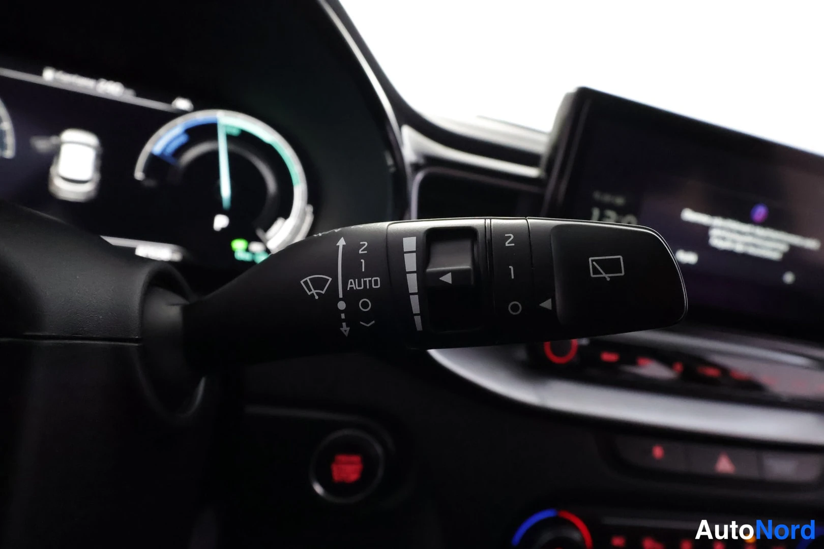 Muu: Tuulilasinpyyhkijän varren lähikuva AUTO-asennolla, taustalla digitaalinen mittaristo ja infotainment-näyttö.