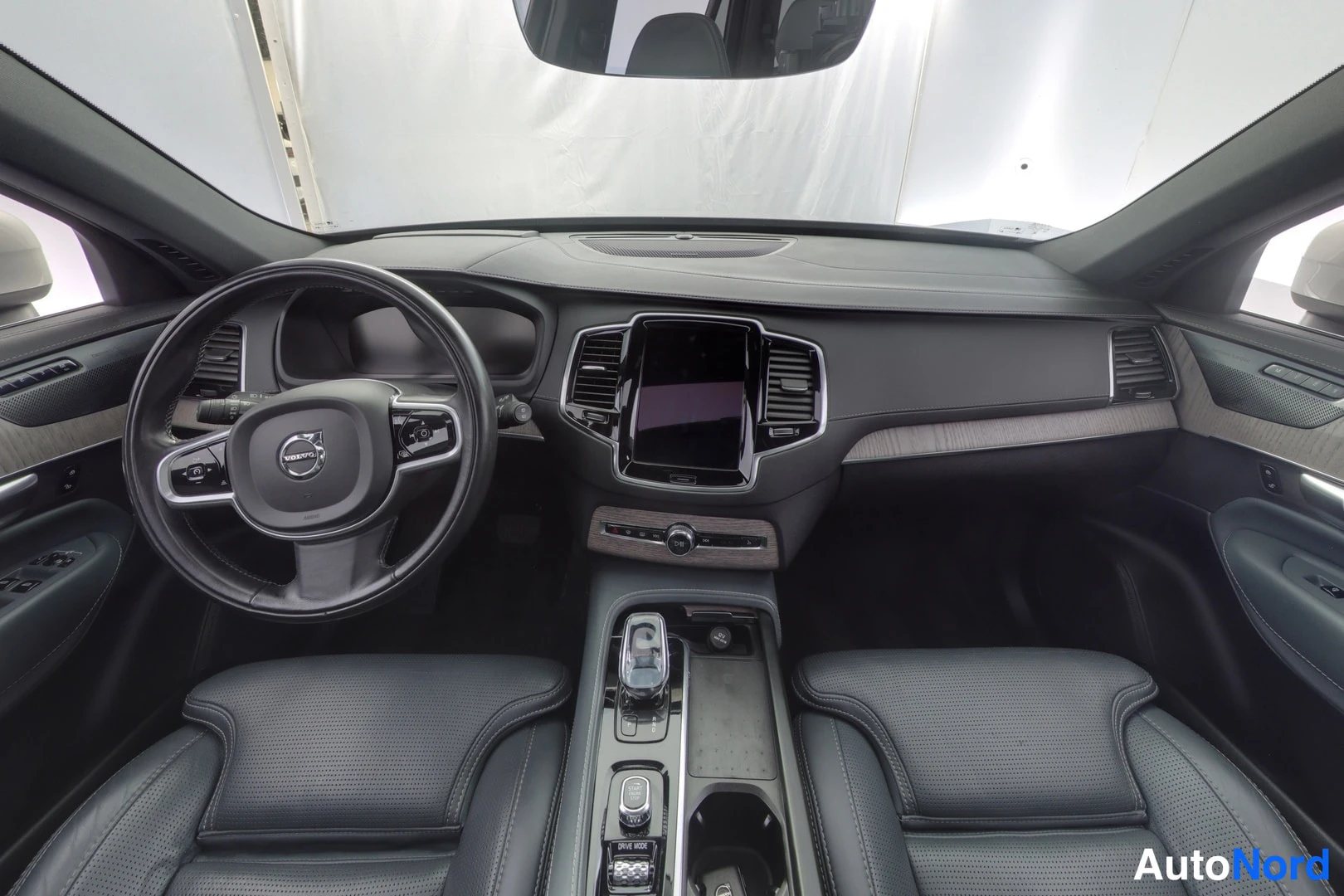 Yksityiskohta: Ohjaamo etuistuimilta kuvattuna: mustat nahkaistuimet, Volvo-ohjauspyörä, keskellä pystytäyttöinen kosketusnäyttö ja automaattivaihteen valitsin.