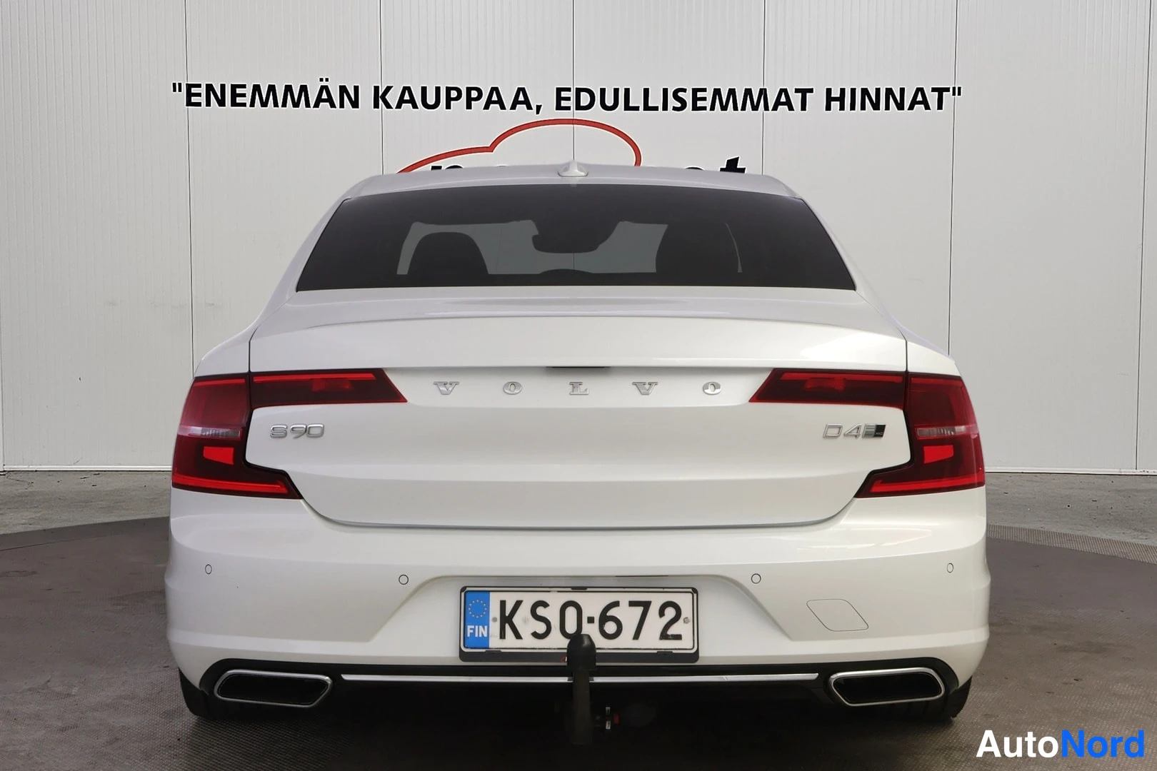 Takaa: Auton takaosa suoraan takaa: valkoinen sedan, rekisterikilpi.