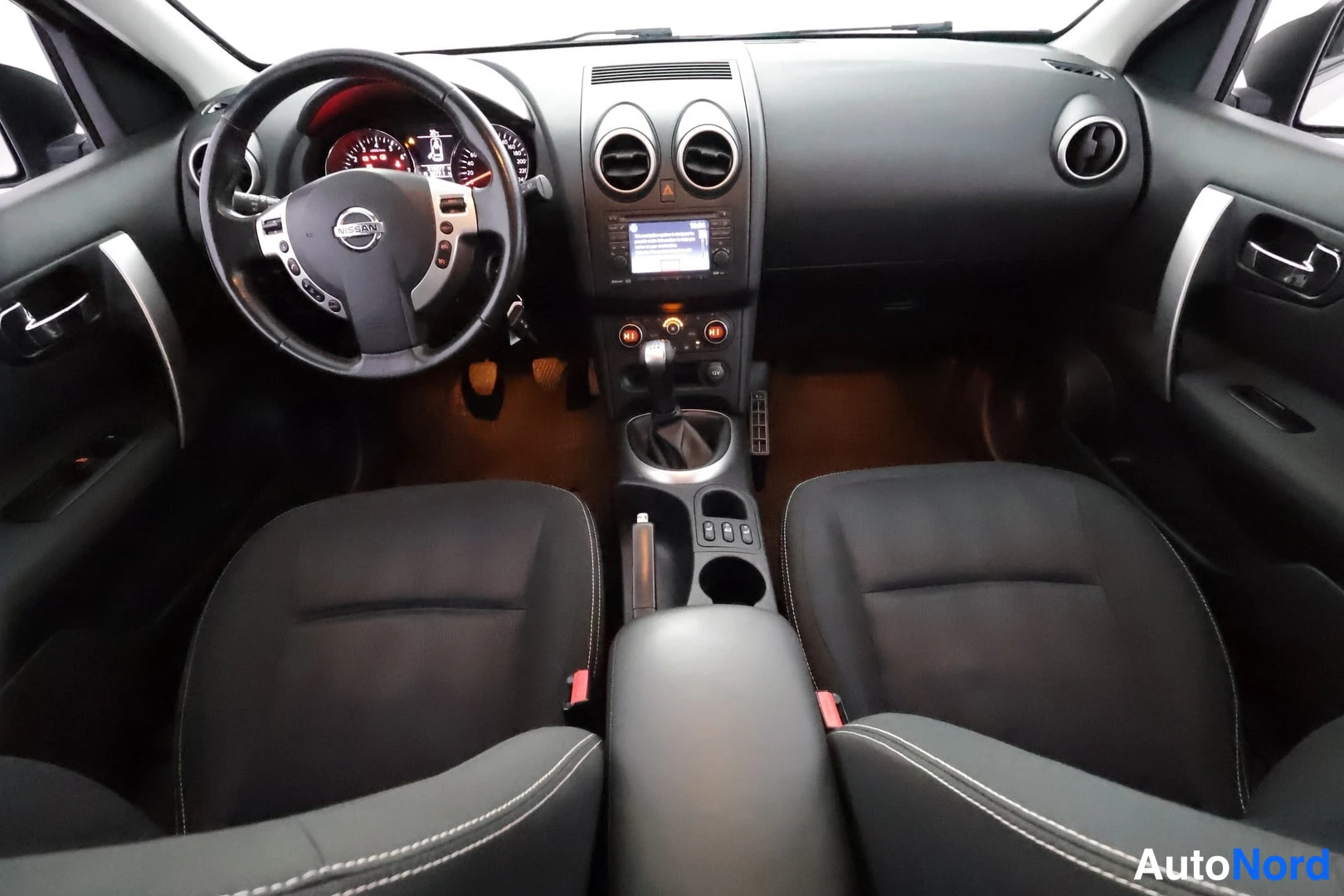 Edestä: Ohjaamo etupästä: Nissan-ohjauspyörä, manuaalivaihteisto, mittaristo ja radiopaneeli, kaksi etuistuinta.