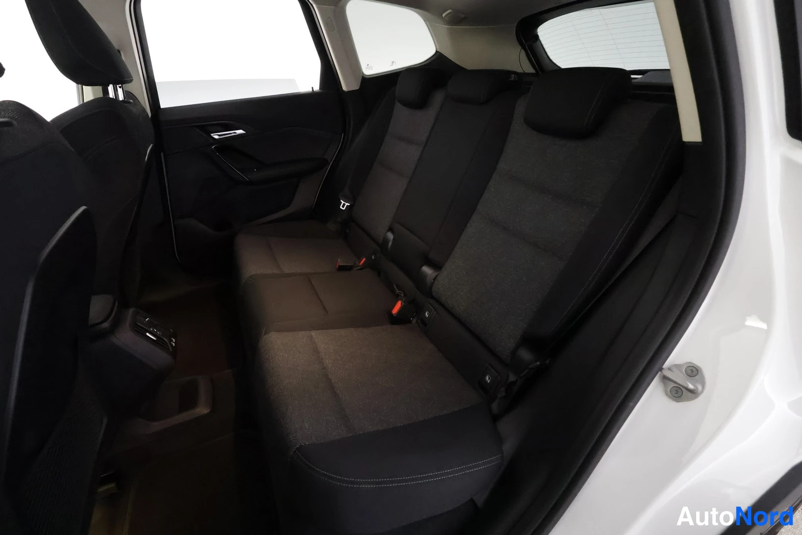 Muu: Sisäkuva takaistuimelle katsoen: takaistuin ja ovin paneli, tumma kangasverhoilu, turvavyöt ja ISOFIX-kiinnikkeiden merkit näkyvissä.