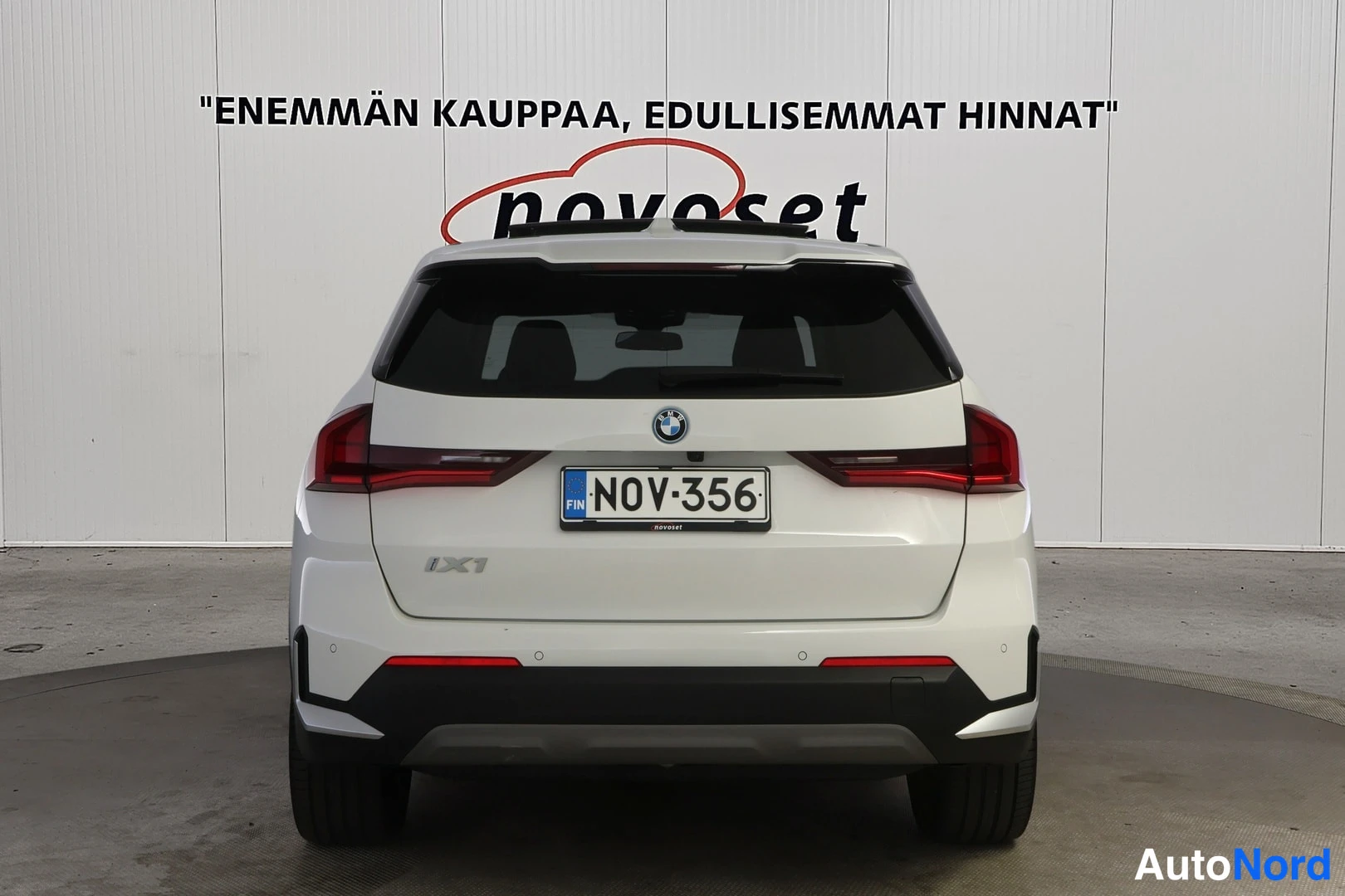 Takaa: Valkoinen BMW iX1 suoraan takaa kuvattuna, takaluukussa iX1-tunnus, rekisteritunnus.