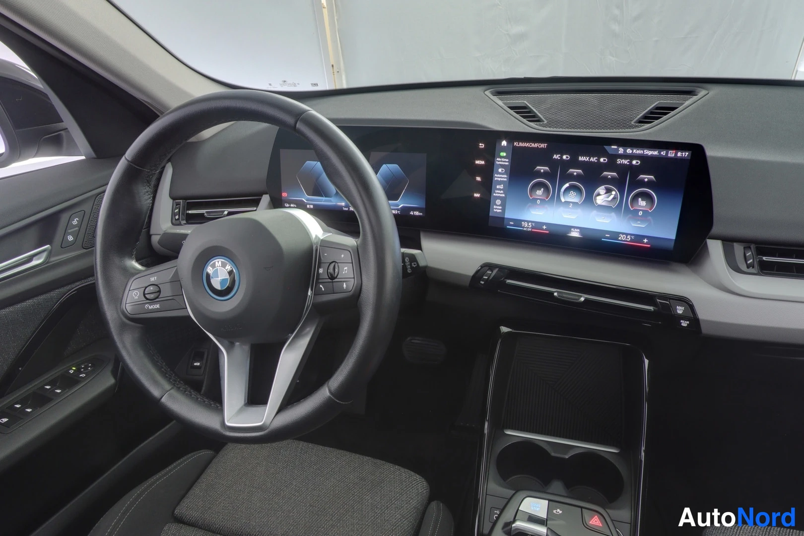 Yksityiskohta: Interior close-up of the driver’s side with a multifunction steering wheel, digital instrument cluster, and infotainment screen displaying climate controls (19.