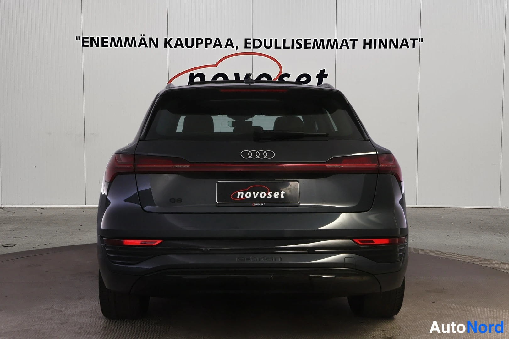 Takaa: Suora takanäkymä Audi Q8 e-tron -maasturin perästä studiossa; perälaatalla Q8-merkki, Audi-neljän renkaan tunnus ja novoset-kyltti rekisterikilven paikalla.