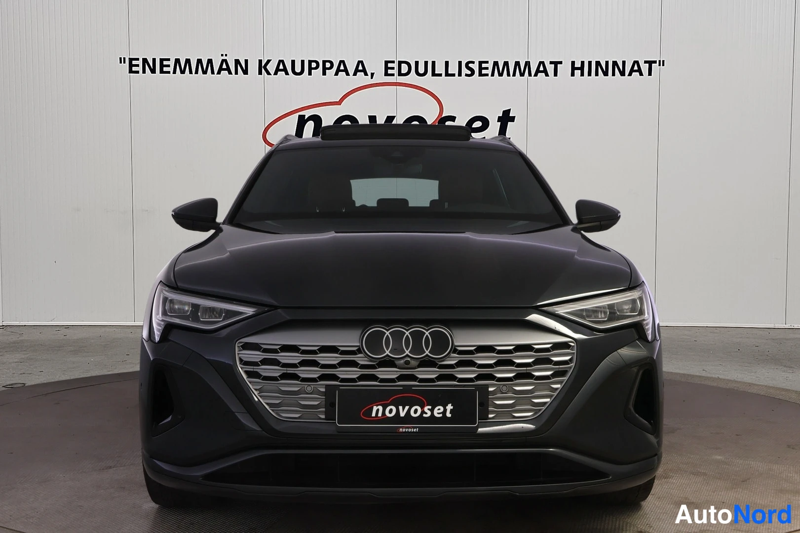 Edestä: Kuvassa näkyy etupäältä auto, jolla on suuri eturistikko ja Audi-logot.
