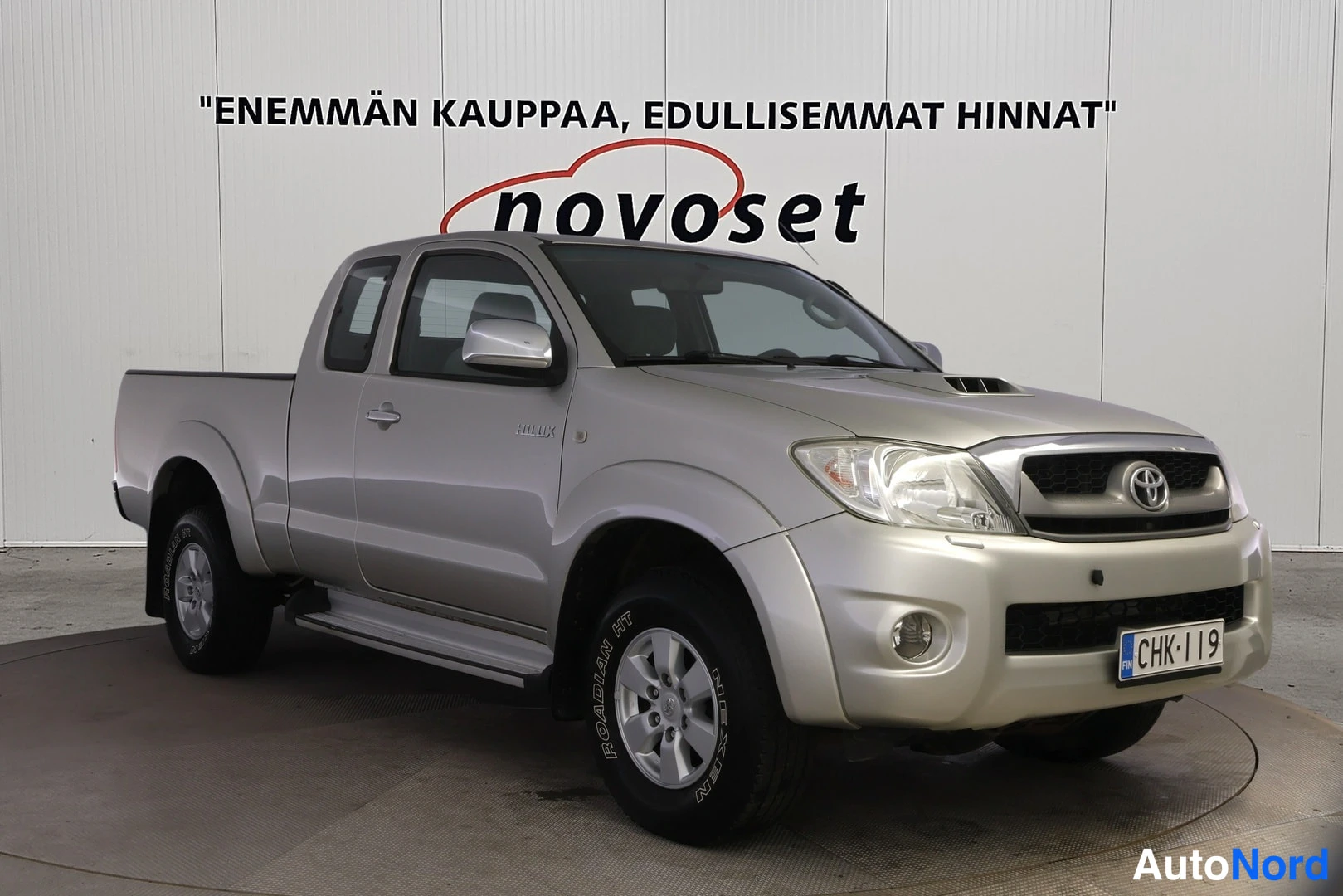 Etuviisto, nokka oikealle: Hopeanvärinen Toyota Hilux -lava-auto kuvattuna etukulmasta, keula kuvan oikealla puolella.