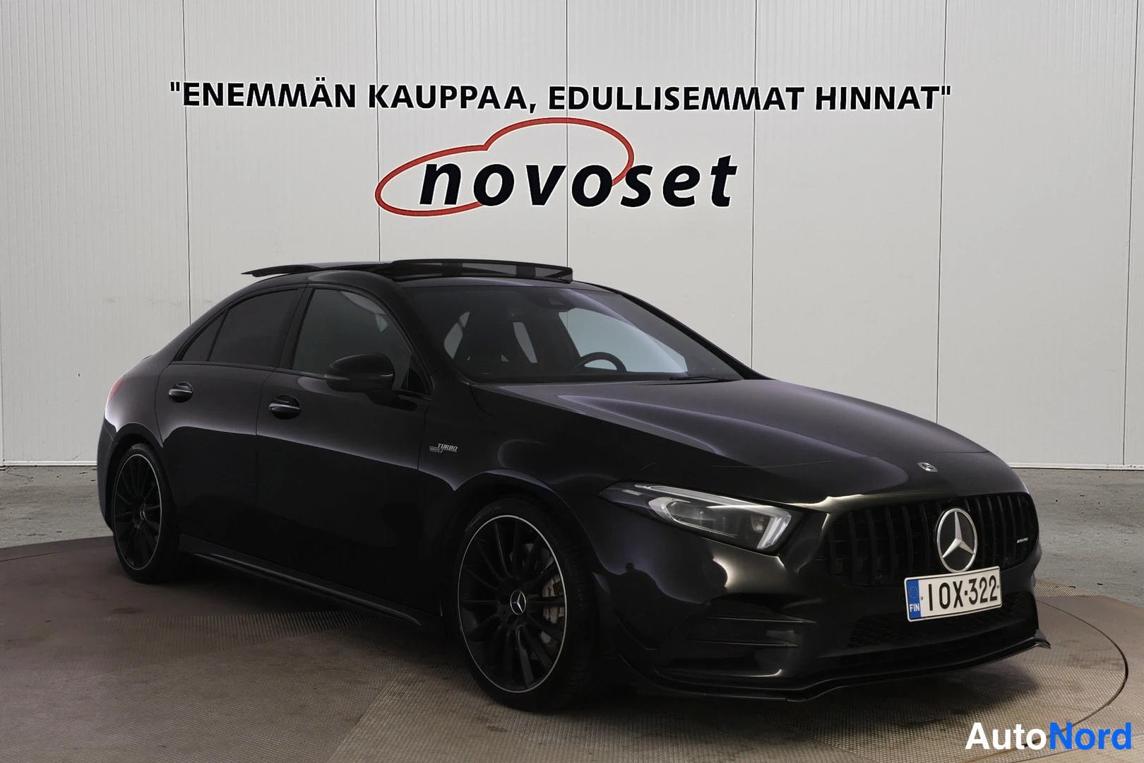 Etuviisto, nokka oikealle: Musta Mercedes-Benz A 35 AMG -sedan etukulmakuvassa keula oikealla; panoraamikatto, pystysäleikköinen keulagrilli Mercedes-tähdellä ja tummat kevytmetall