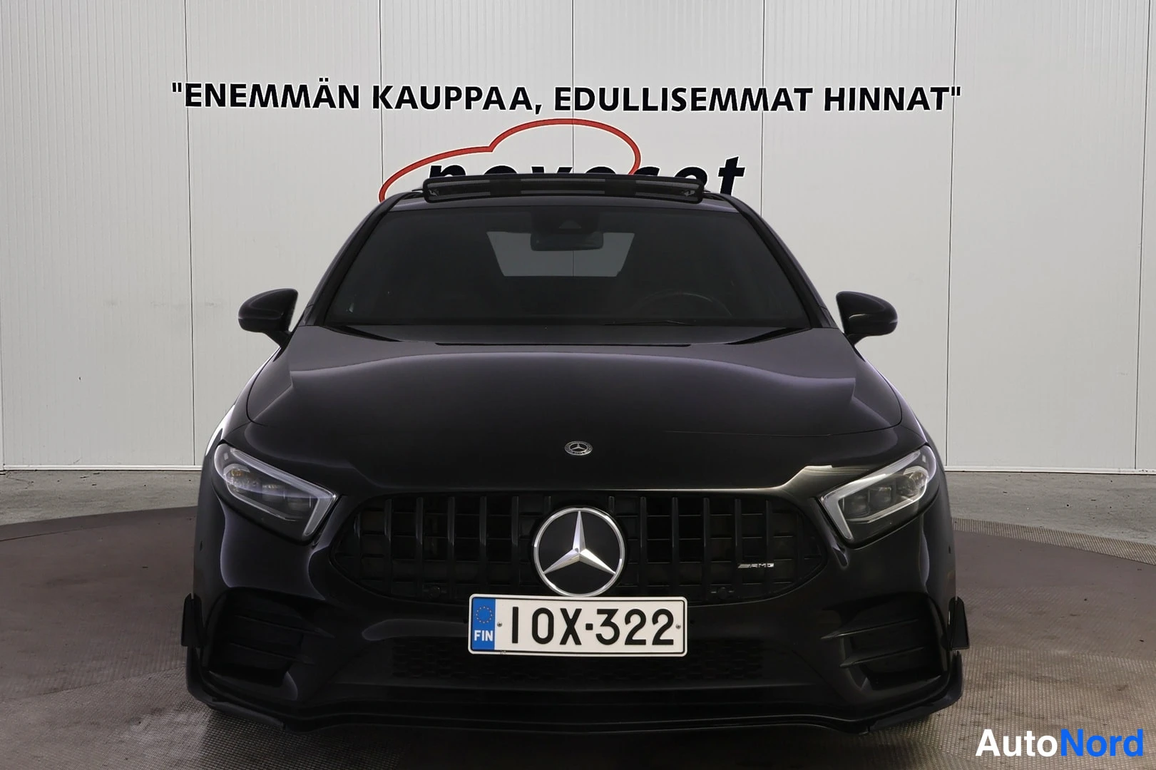 Edestä: Mercedes-Benz A 35 AMG suoraan edestä; musta pystysäleikköinen grilli AMG-tekstillä, ajovalot ja rekisterikilpi.