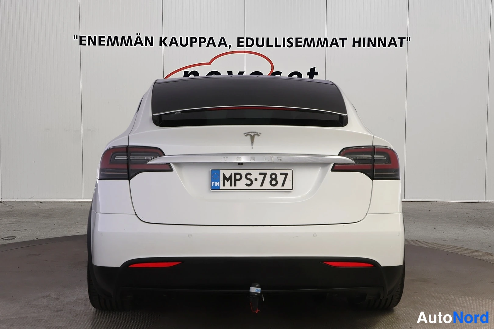 Takaa: Tesla Model X:n takaosa suoraan takaa, valkoinen kori, Tesla-merkki ja rekisterikilpi, vetokoulu alla.