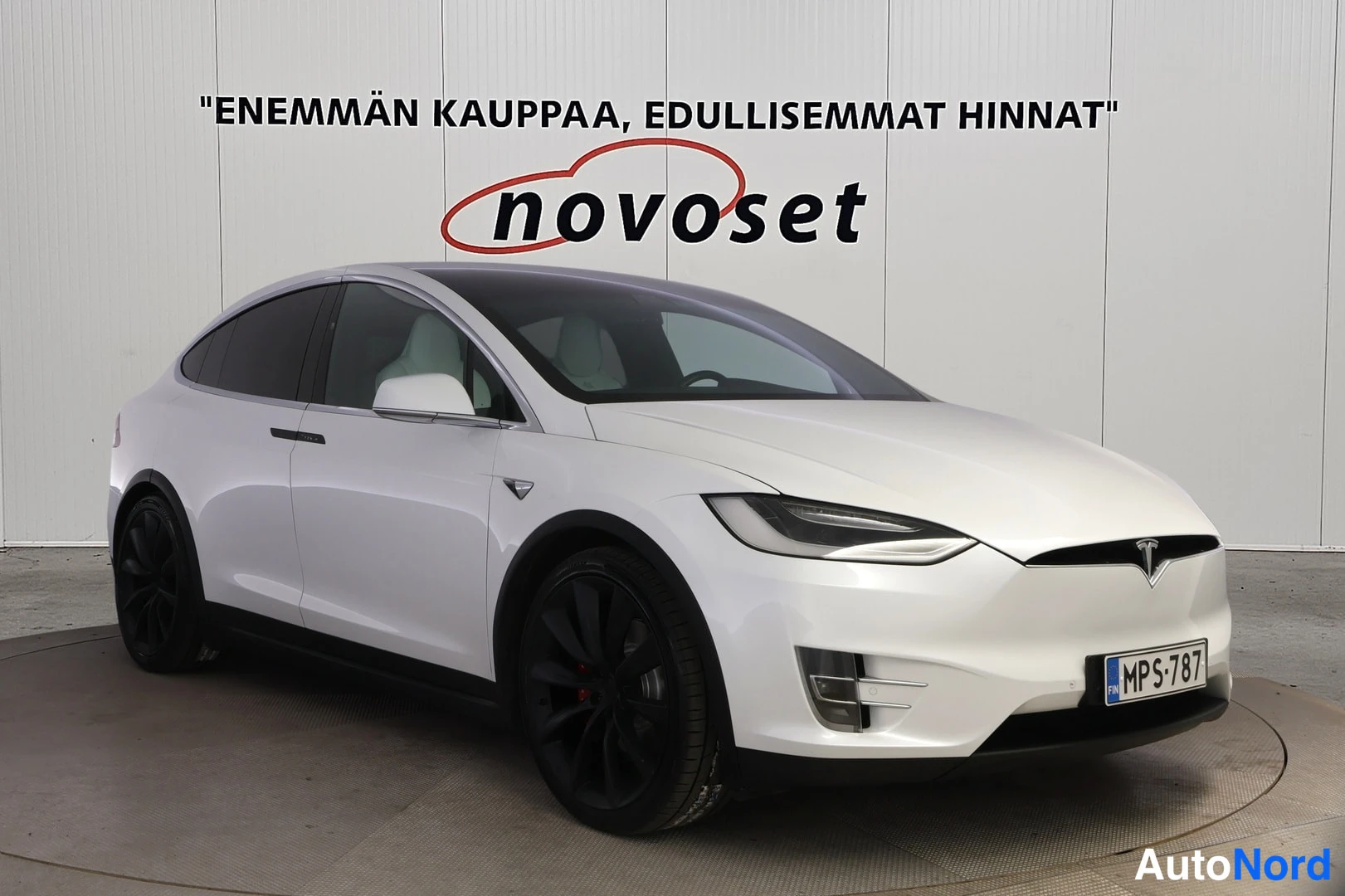Etuviisto, nokka oikealle: Valkoisen farmarihatchbackin kolmeneljäsosan etunäkymä, keula kuvan oikealla puolella, mustat kevytmetallivanteet.