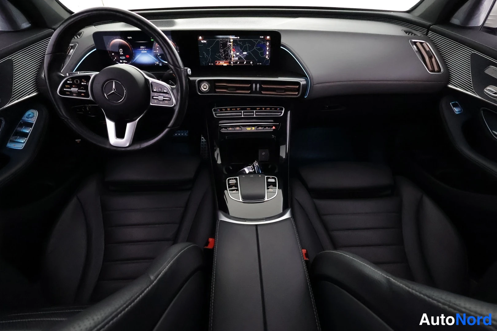 Edestä: Kojelauta ja etuistuimet suoraan edestä: Mercedes-merkkiohjauspyörä, digitaalinen mittaristo, kosketusnäyttö karttanimikkeineen, keskikäytävän säätimet ja musta