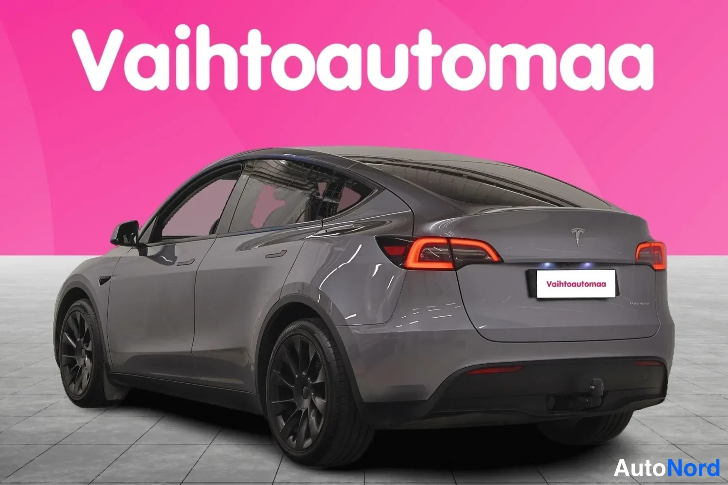 Takaviisto: Tesla Model Y -henkilöauto harmaana takakulmasta, takavalot näkyvissä.