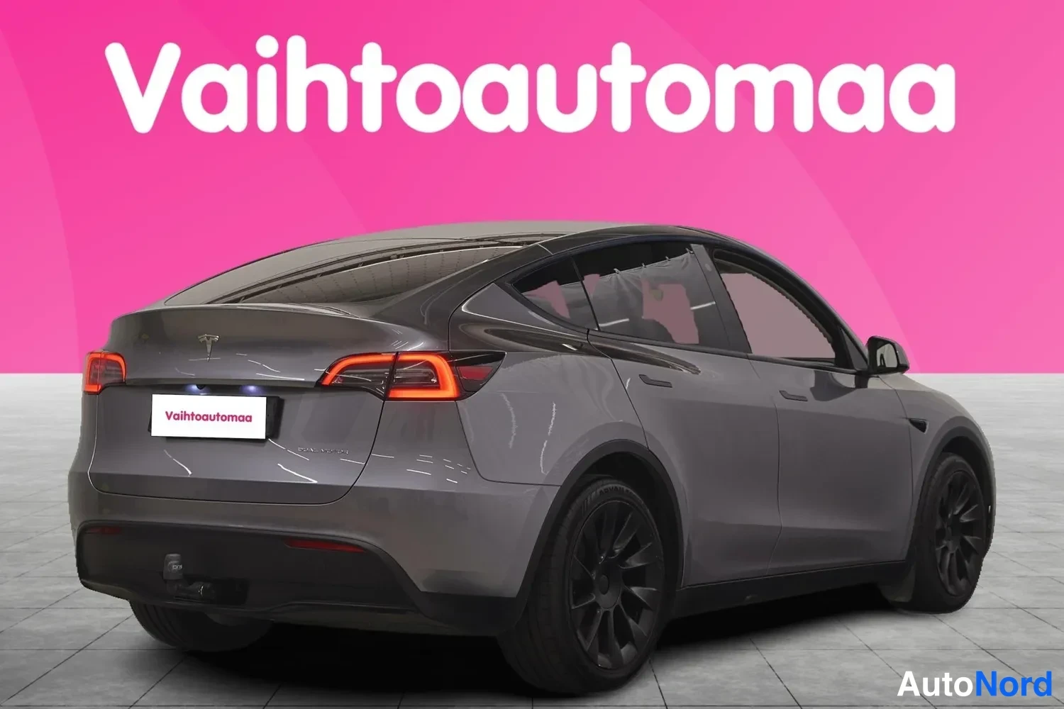 Takaviisto: Tesla Model Y:n takaosan kolmeneljänneskuva vasemmalta, tummanharmaa kori ja mustat vanteet.