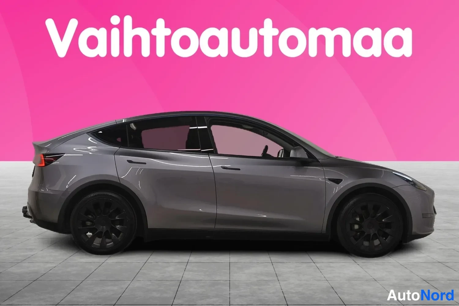 Sivulta: Tesla Model Y sivuprofiilikuva oikealta, tummanharmaa kori ja mustat kevytmetallivanteet.