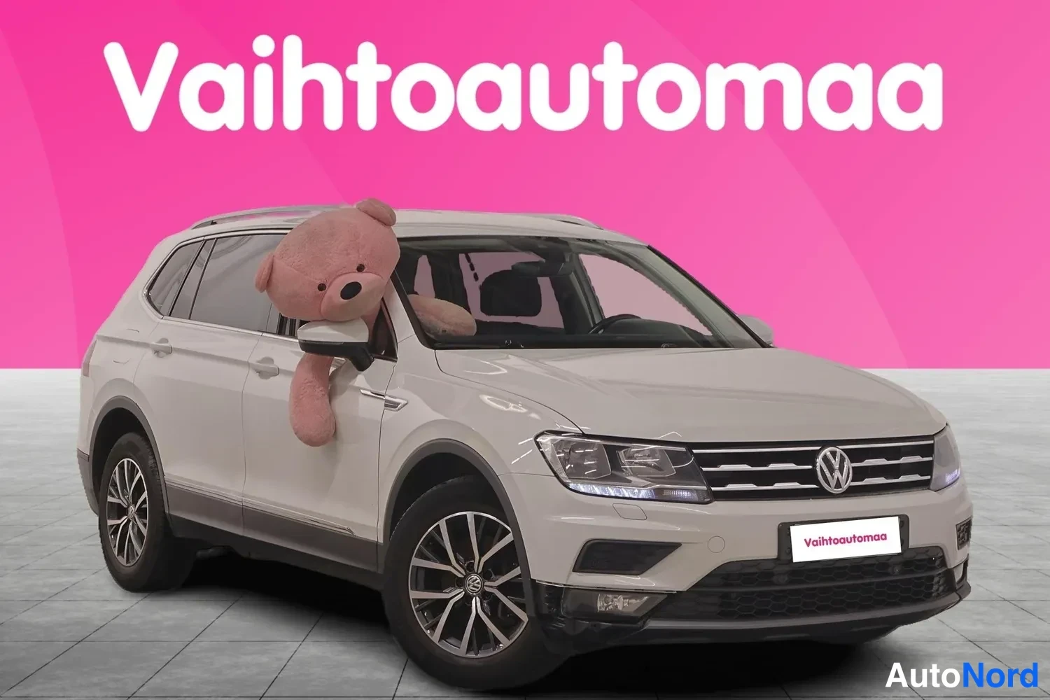 Etuviisto, nokka oikealle: Valkoisen Volkswagen Tiguanin etukulmakuva, keulakuva ja vasen kylki näkyvissä, takarenas pyörii vasemmalla ja etusäleikkö oikealla