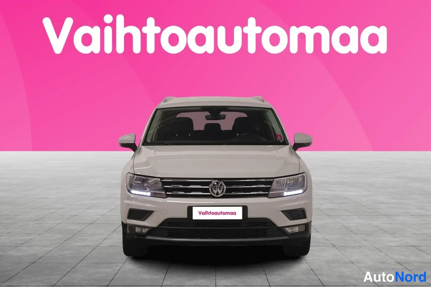 Edestä: Valkoisen Volkswagen Tiguanin suora etunäkymä, keulavilkut ja etusäleikkö näkyvissä