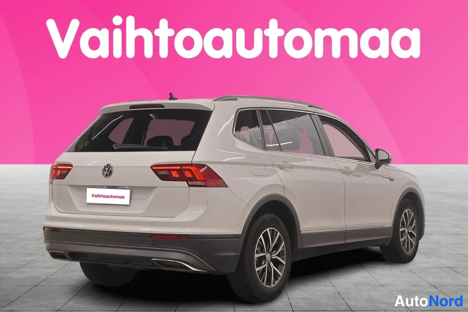 Takaviisto: Valkoinen Volkswagen Tiguan Allspace -farmi-SUV takaa-vasemmalta kuvattuna, takavalot ja tummat kolmiolta näyttävät vanteet näkyvissä.