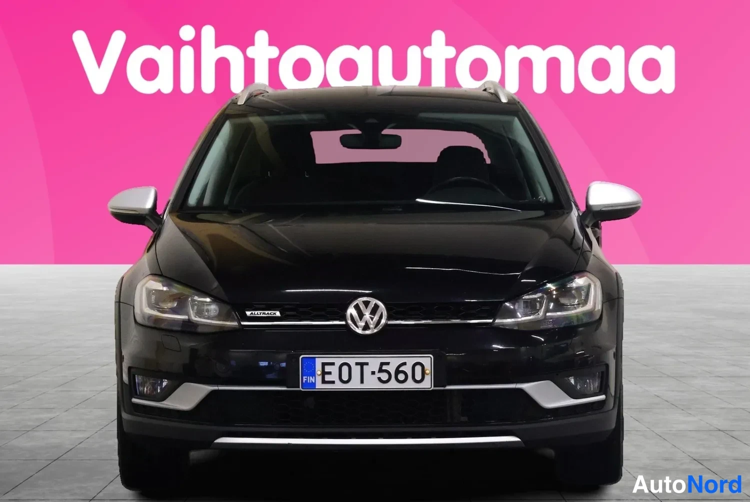 Edestä: Mustan Volkswagenin etunäkymä suoraan edestä, rekisteritunnus, VW-merkki ja etuvalot näkyvät.