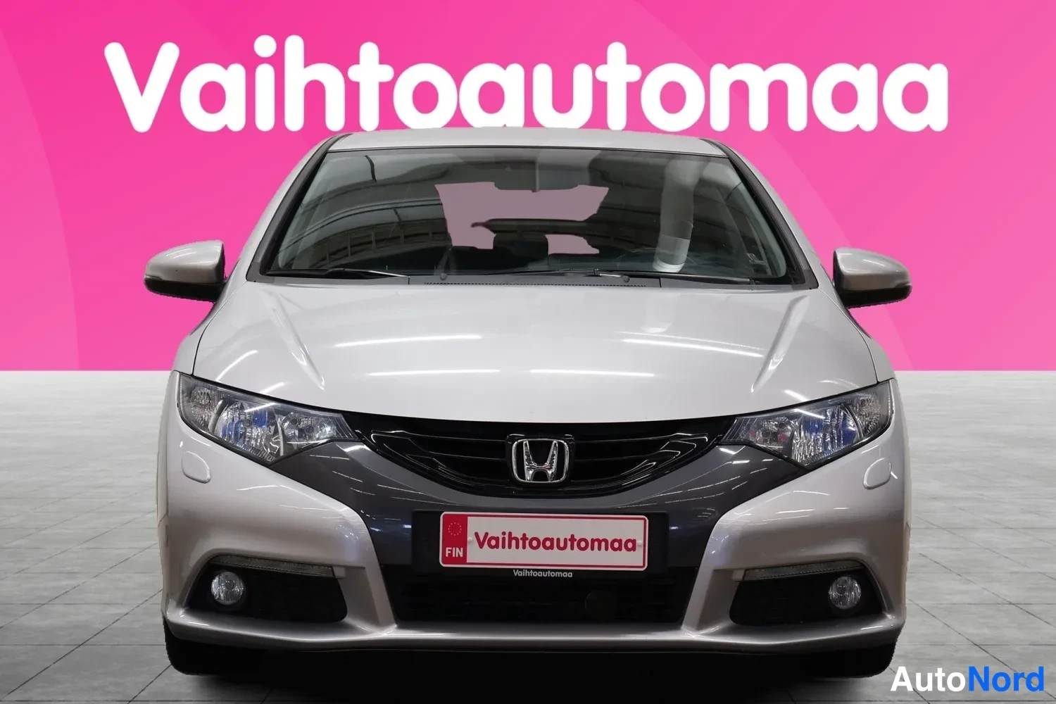 Edestä: Hopeanvärinen Honda-viistoperä suoraan edestä, etusäleikkö ja ajovalot näkyvissä.