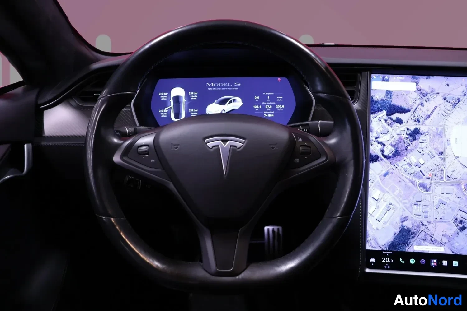 Edestä: Ohjauspyörä ja mittaristo lähikuvassa, näytössä MODEL S -teksti ja ajotietoja; kartta kosketusnäytöllä.