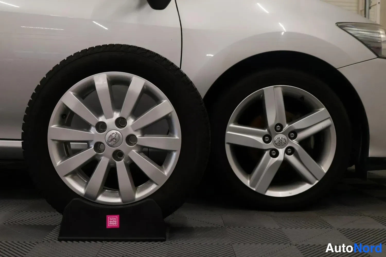 Etuviisto, nokka oikealle: Hopeisen auton etupyörä ja vieressä seisova irtonainen Toyota-alumiinvanne talvirenkaalla