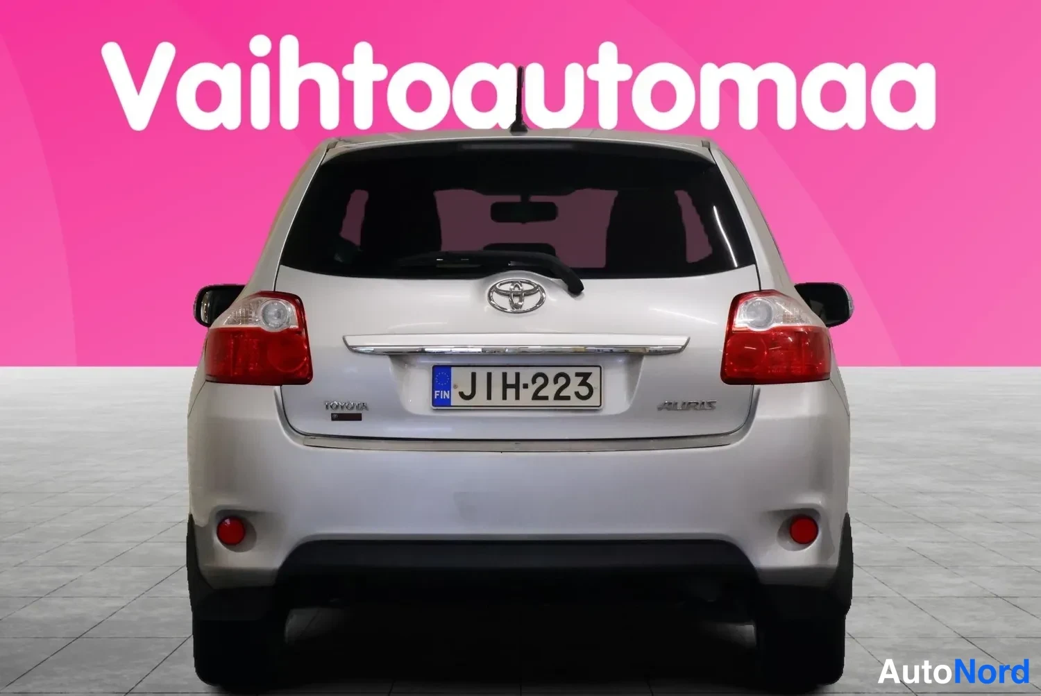 Takaa: Hopeanharmaa Toyota Auris suoraan takaa, rekisterikilpi ja Toyota-emblem näkyvissä.