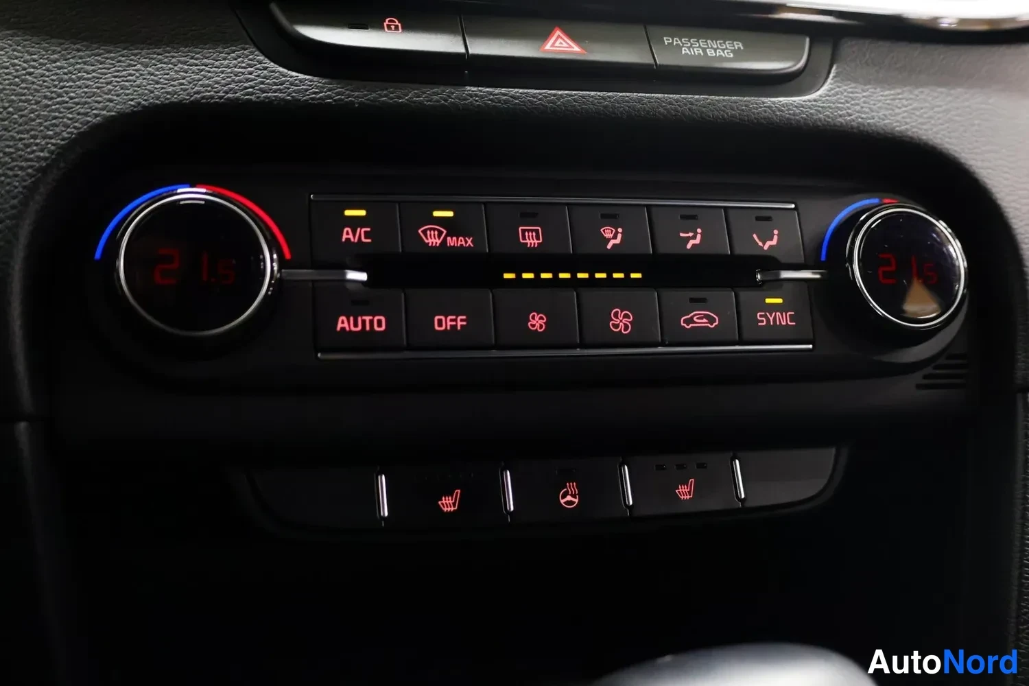 Muu: Lähikuva keskus console -ilmastointipaneelista, jonka molemmissa reunoissa on 21 asteen digitaalinäytöt ja jossa on painikkeet A/C, AUTO, OFF, SYNC, MAX Defrost
