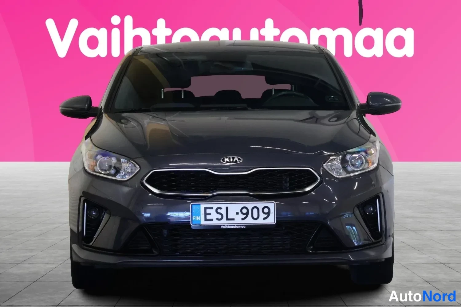 Edestä: Auton etupäädystä suoraan otettu kuva, tummanharmaa koriväri, rekisteritunnus.