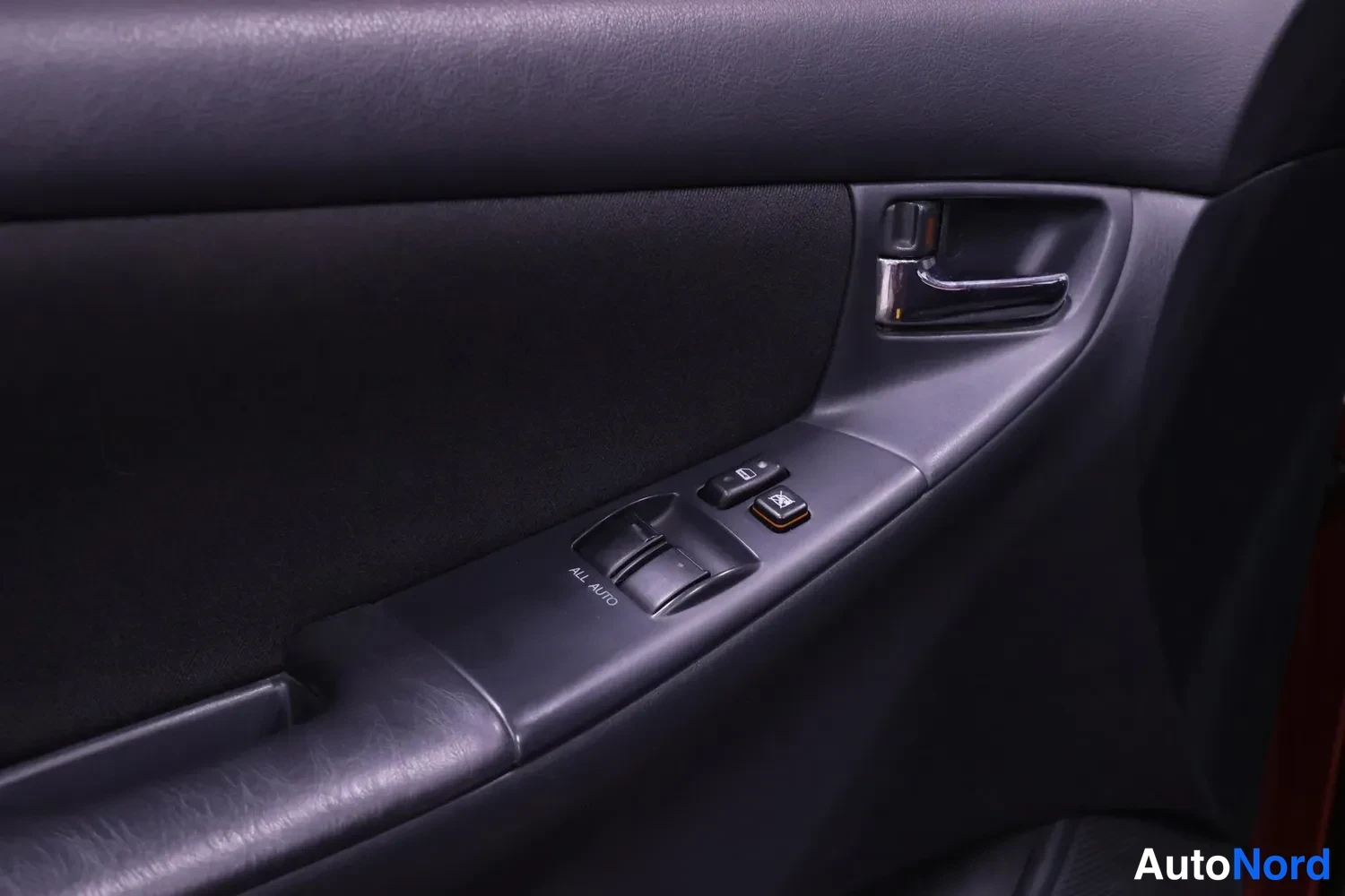 Yksityiskohta: Oven sisäpaneeli: kromattu sisäkahva ja sähköikkunakytkimet, merkintä ALL AUTO.