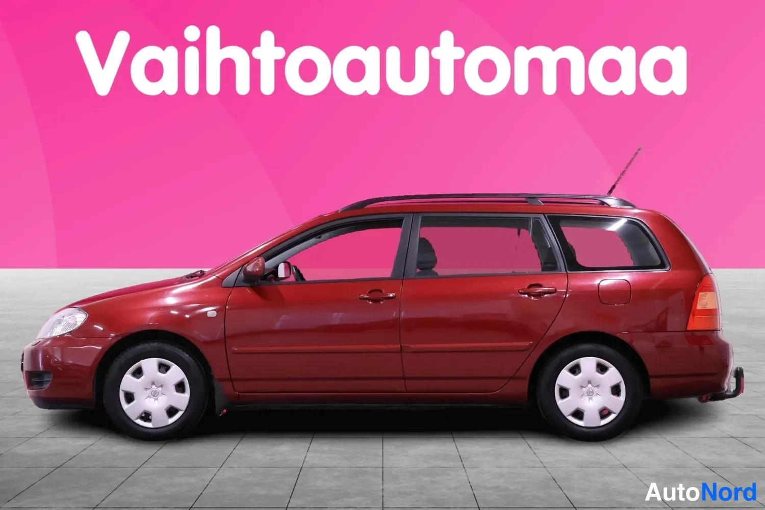 Sivulta: Tummanpunainen Toyota Corolla -farmari sivulta kuvattuna; korotut kattokaiteet ja peilit näkyvissä.