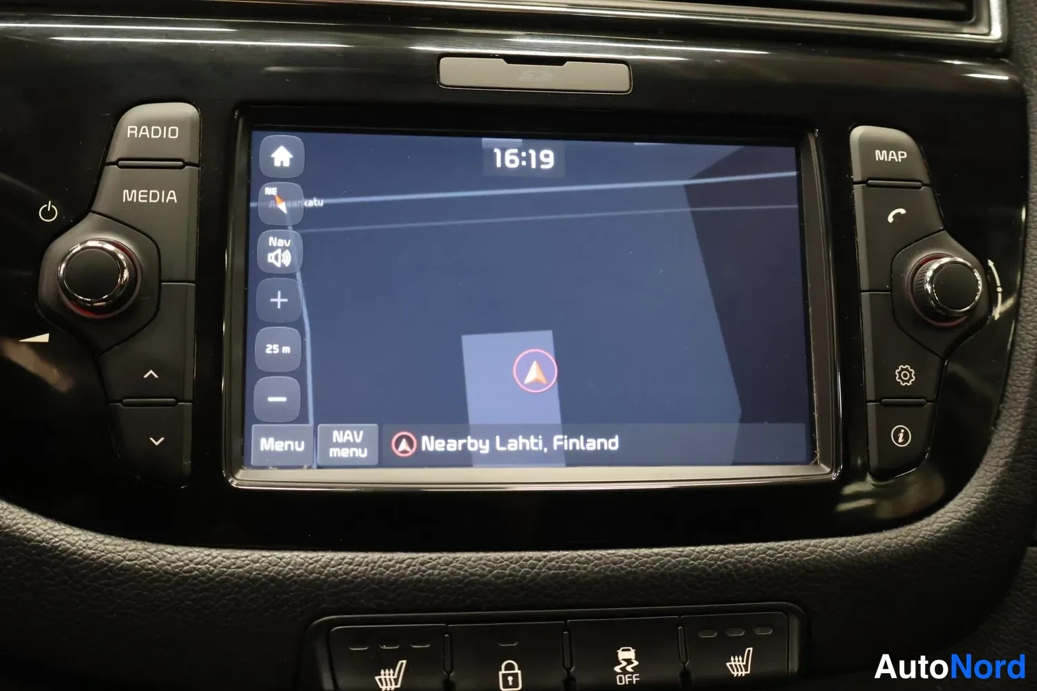 Yksityiskohta: Infotainment-näyttö navigointinäkymässä, 25 m:n ohje ja teksti 'Nearby Lahti, Finland', alapuolella painikkeita istutinlämmityksestä ja ajonvakautuksesta.