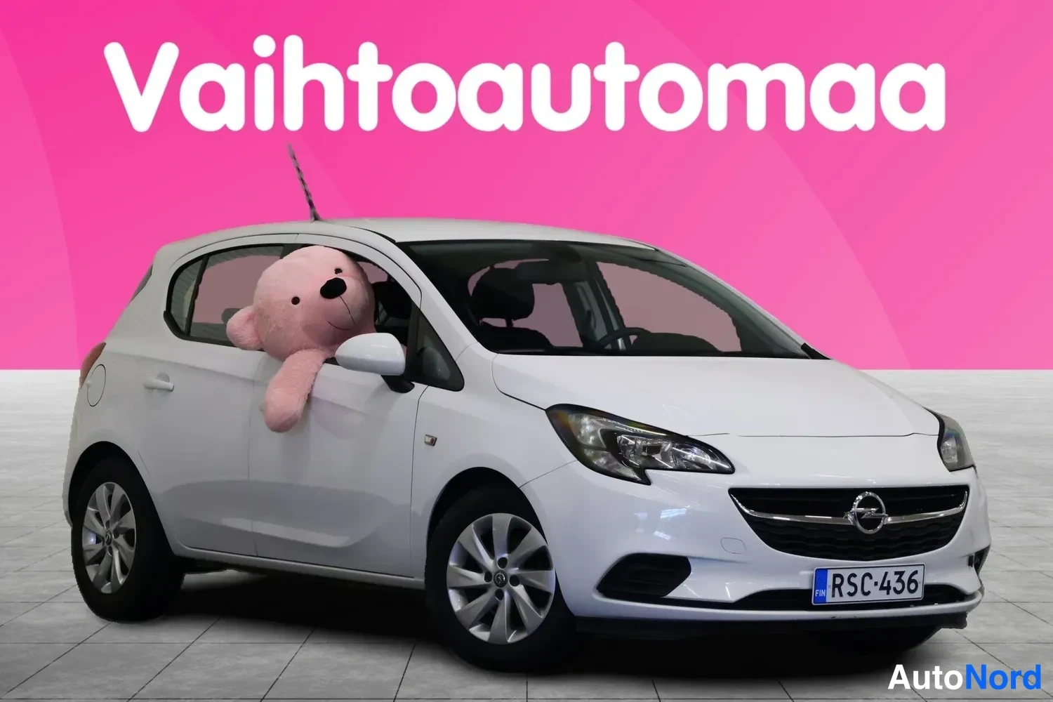 Etuviisto, nokka oikealle: Valkoinen Opel Corsa -henkilöauto kolmesta neljästä etukulmasta, keulakulta oikealla, rekisterikilpi.