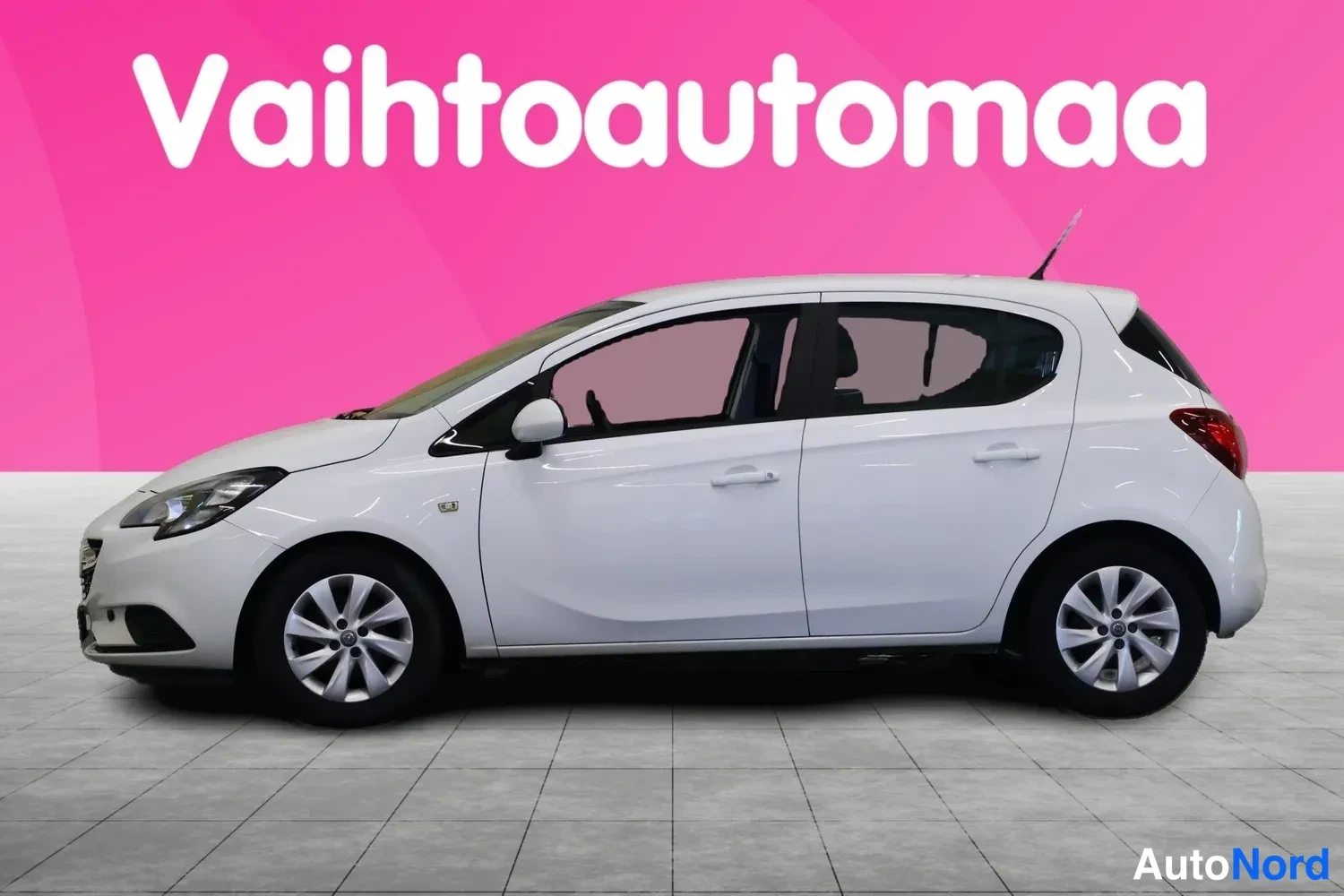 Sivulta: Valkoinen Opel Corsa -henkilöauto sivulta oikealta, neliovinen hatchback, pinkki tausta.