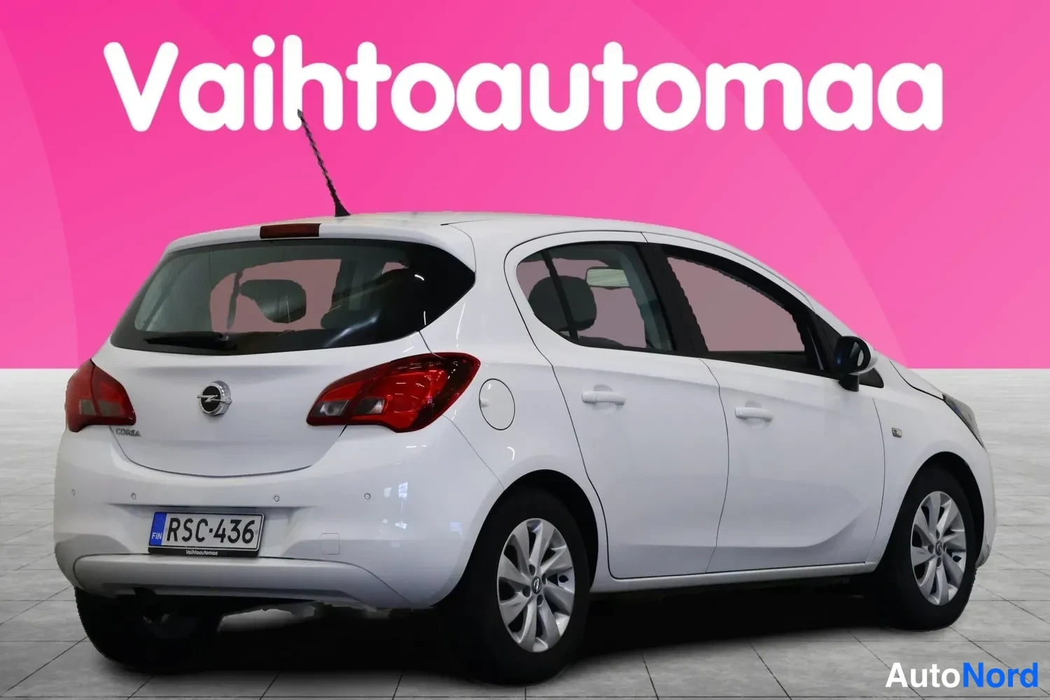Takaviisto: Auton takanurkkikuva vasemmalta: valkoinen Opel Corsa, takavalot ja rekisteritunnus näkyvät.