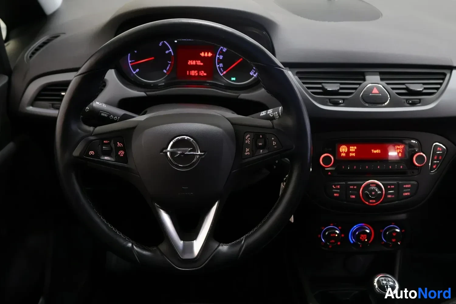 Muu: Ohjaamon kuva: Opel-merkkinen ohjauspyörä, kojetaulun näyttö ja keskikonsolon radio ja lämmityksensäätimet.