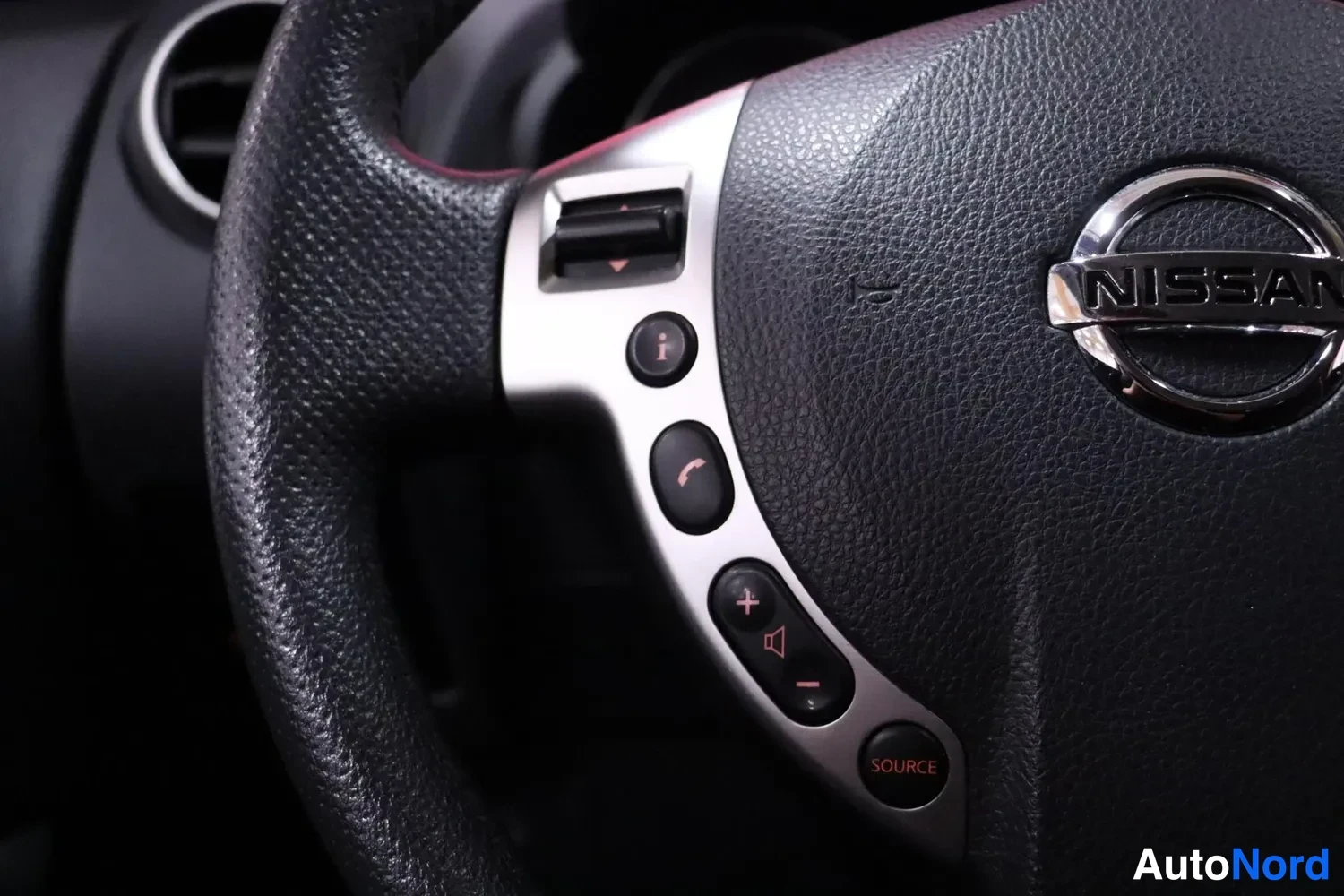 Muu: Ohjauspyörän vasen puoli, jossa Nissan-logo ja äänentoiston ja puhelun painikkeet.