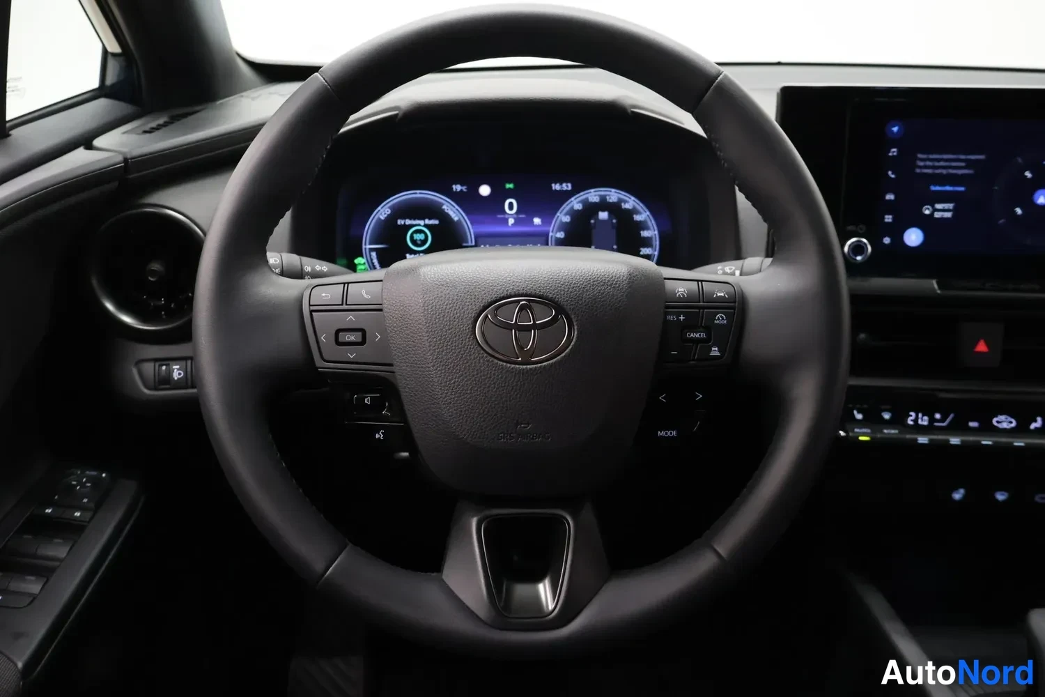 Muu: Etunäkymä Toyota-ohjauspyörästä ja digitaalisesta mittaristosta, jossa lukee 'EV Driving Ratio', sekä kosketusnäytöstä.