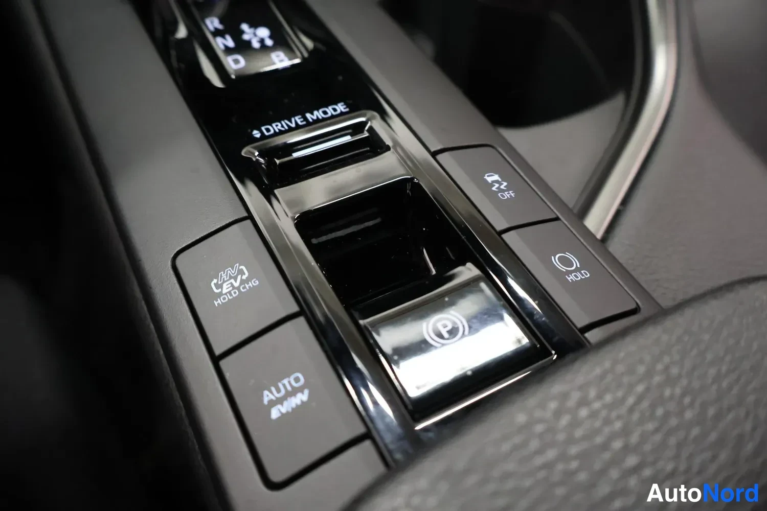 Muu: Keskikonsolin lähikuva: R-, N-, D- ja B-vaihtopainikkeet, DRIVE MODE -valitsin, chrome-tyylinen (P)-sähkökäsisjarrukytkin sekä AUTO AWD-, HV EV HOLD CHG-, HOLD-