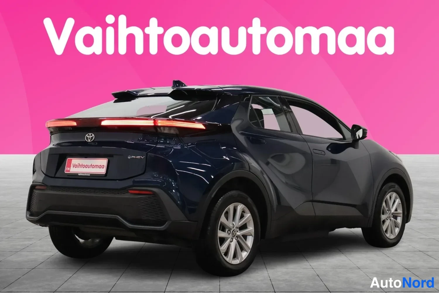 Takaviisto: Sininen Toyota C-HR takaviistosta oikealta, takavalot ja kattospoileri näkyvissä.