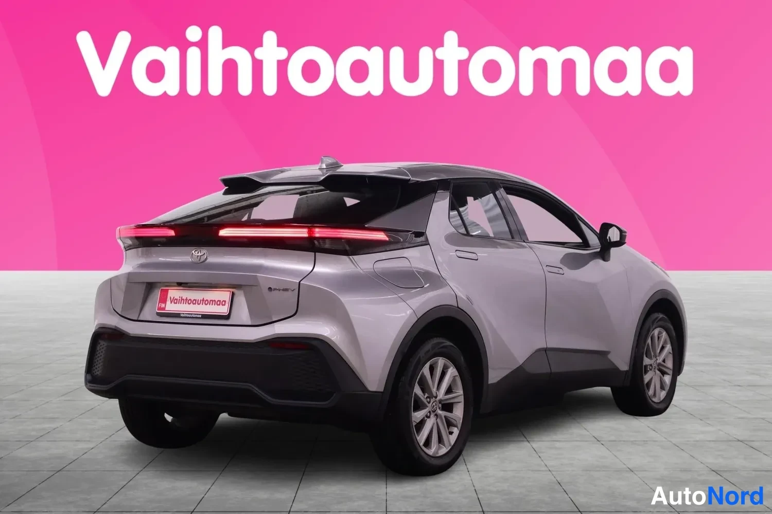 Takaviisto: Hopeanharmaa Toyota C-HR takaa viistosti kuvattuna, punaiset takavalot ja Toyota-merkni näkyvät, tausta pinkki Vahtoautomaa-mainoslogo.