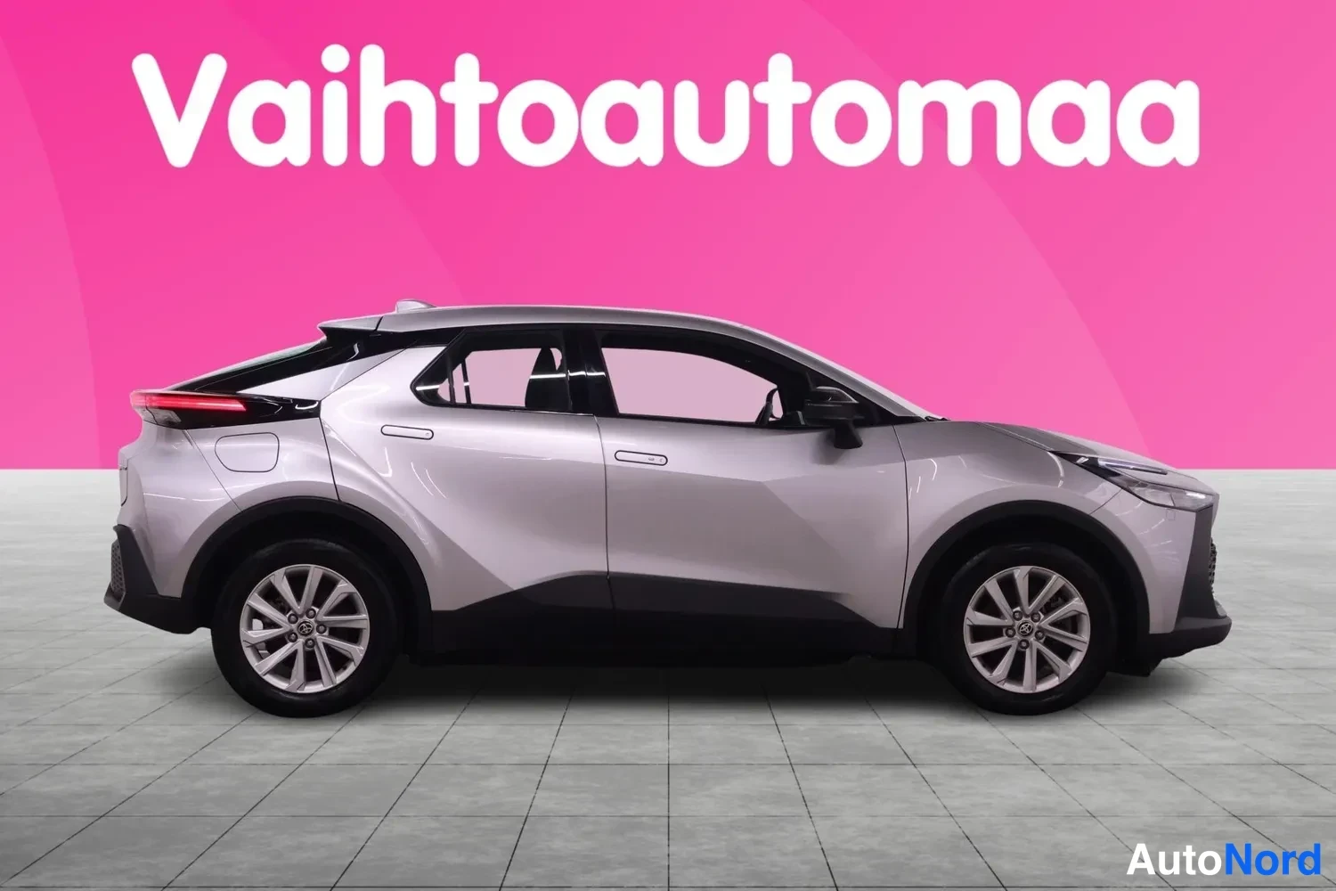 Etuviisto, nokka oikealle: Hopeanharmaa Toyota C-HR sivulta etuosaa viistosti, keulat beisissä oikealla, mustat muovilistat ja katolla tumma kontrastiväri.