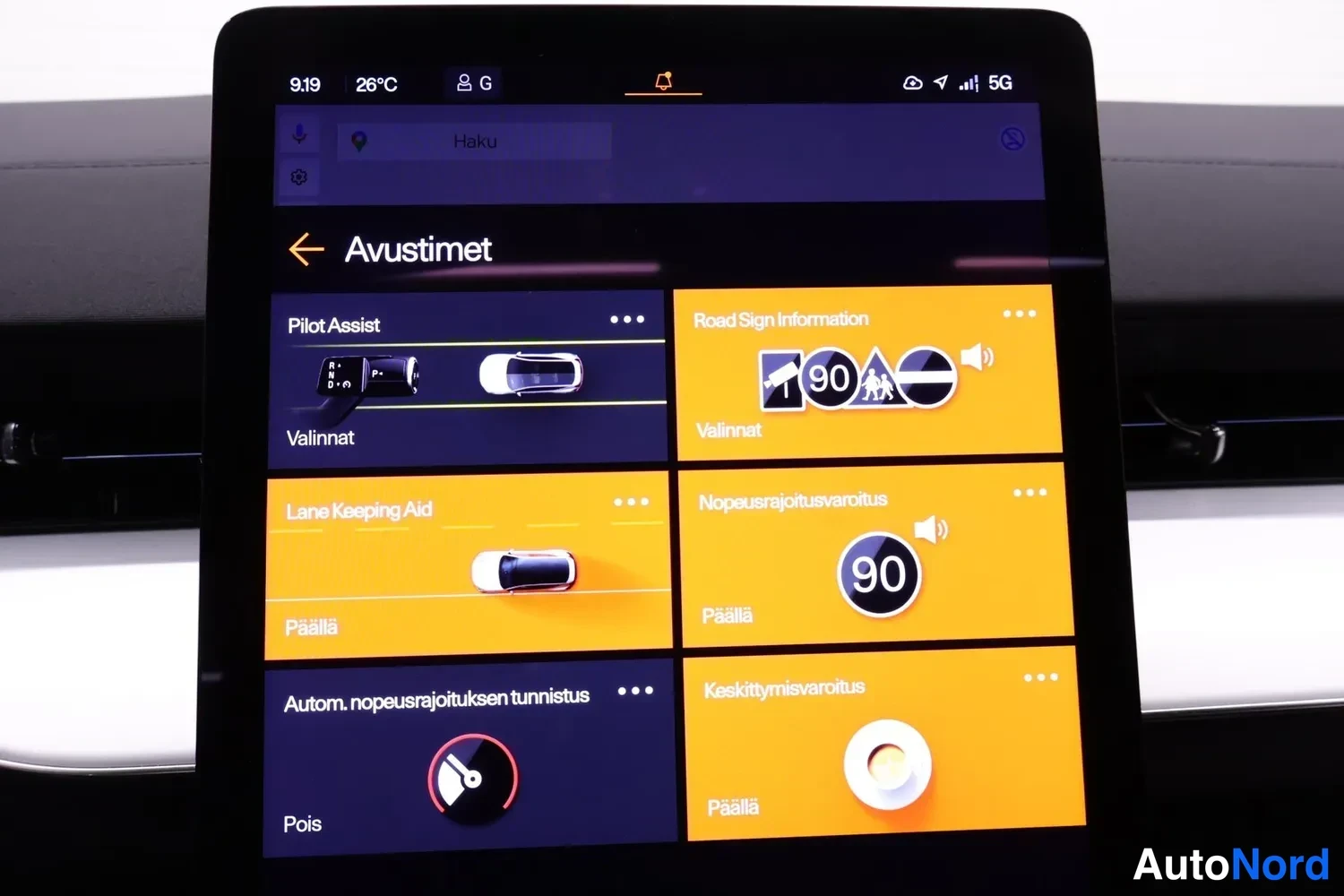 Muu: Keskikonsolin kosketusnäytön Avustimet-näkymä, jossa asetukset Pilot Assistille, Road Sign Informationlle, Lane Keeping Aidille, Nopeusajoitusvaroitukselle, aut