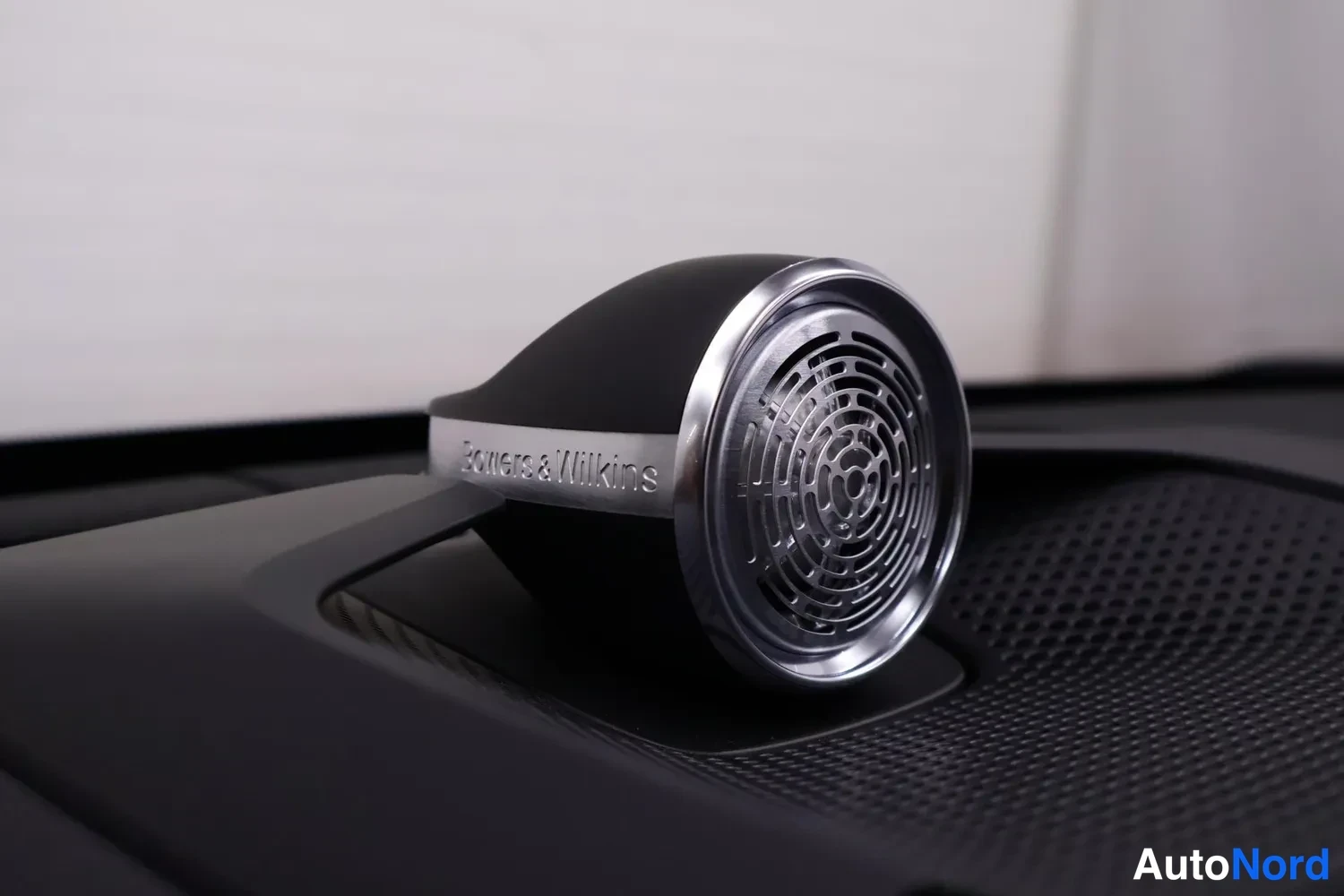 Yksityiskohta: Lähikuva auton kojelaudassa olevasta Bowers & Wilkins -diskanttikaiuttimesta; metallirenkaassa on kaiverrettu teksti 'Bowers & Wilkins'.