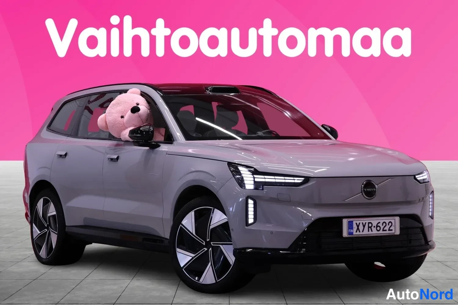 Etuviisto, nokka oikealle: Etukulmakuva vaaleanharmaasta tilavasta SUV-korista, keula oikealla: musta lasikatto, mustat kevytmetallivanteet, rekisterikilpi. Etuikkunassa vaaleanpun