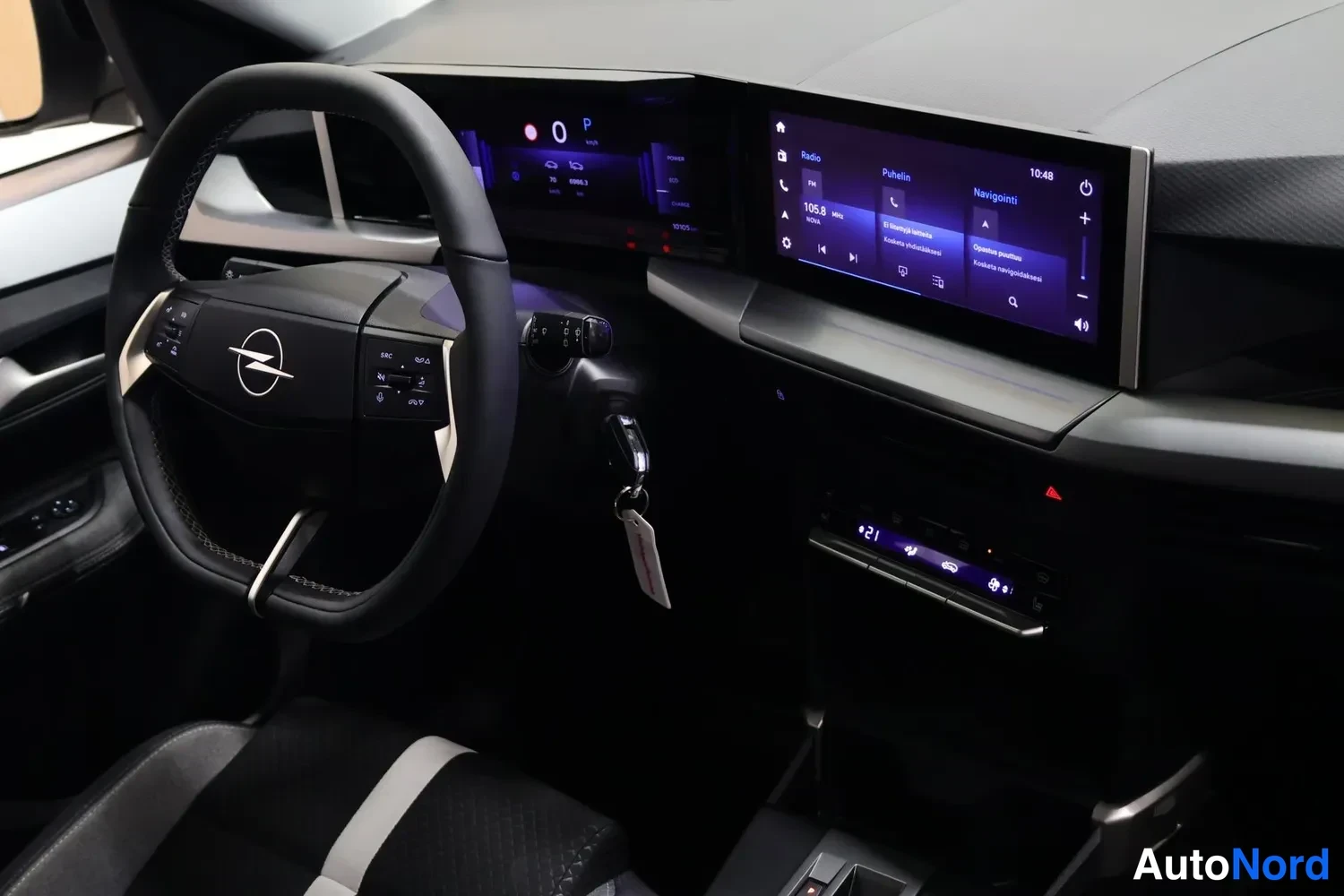 Muu: Opel-merkkinen ohjauspyörä, digitaalinen mittaristo ja kosketusnäyttö, jossa näkyy radio-, puhelin- ja navigointivalikko.