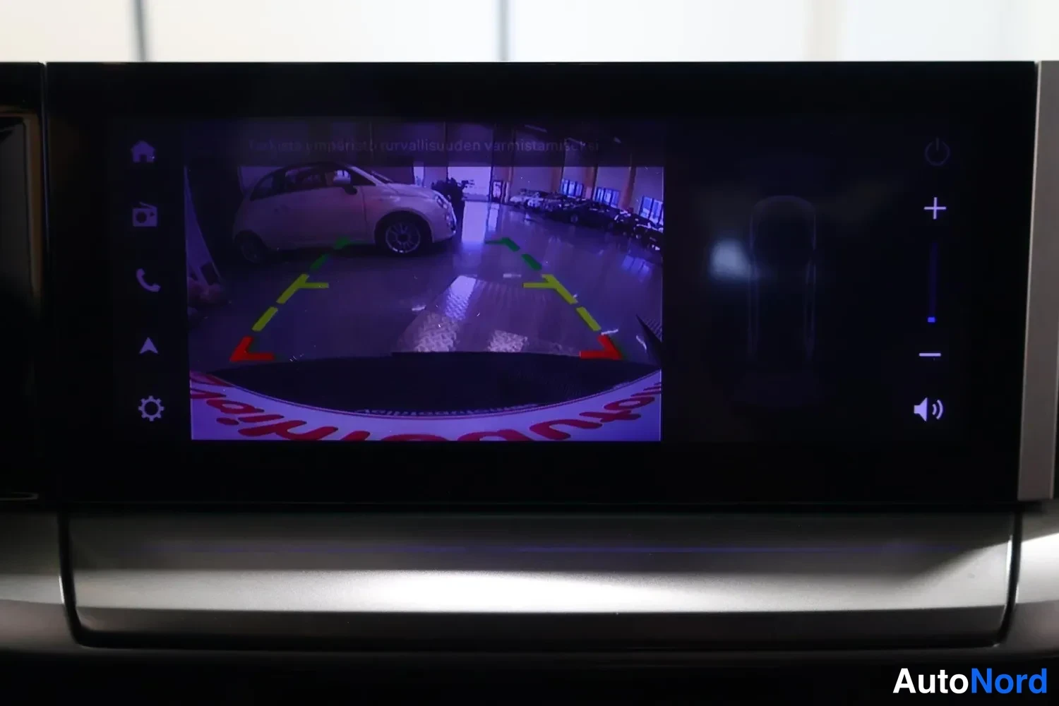 Muu: Infotainment-näyttö, jolla näkyy peruutuskameran kuva vihrein, keltasin ja punaisin ohjausviivoin.